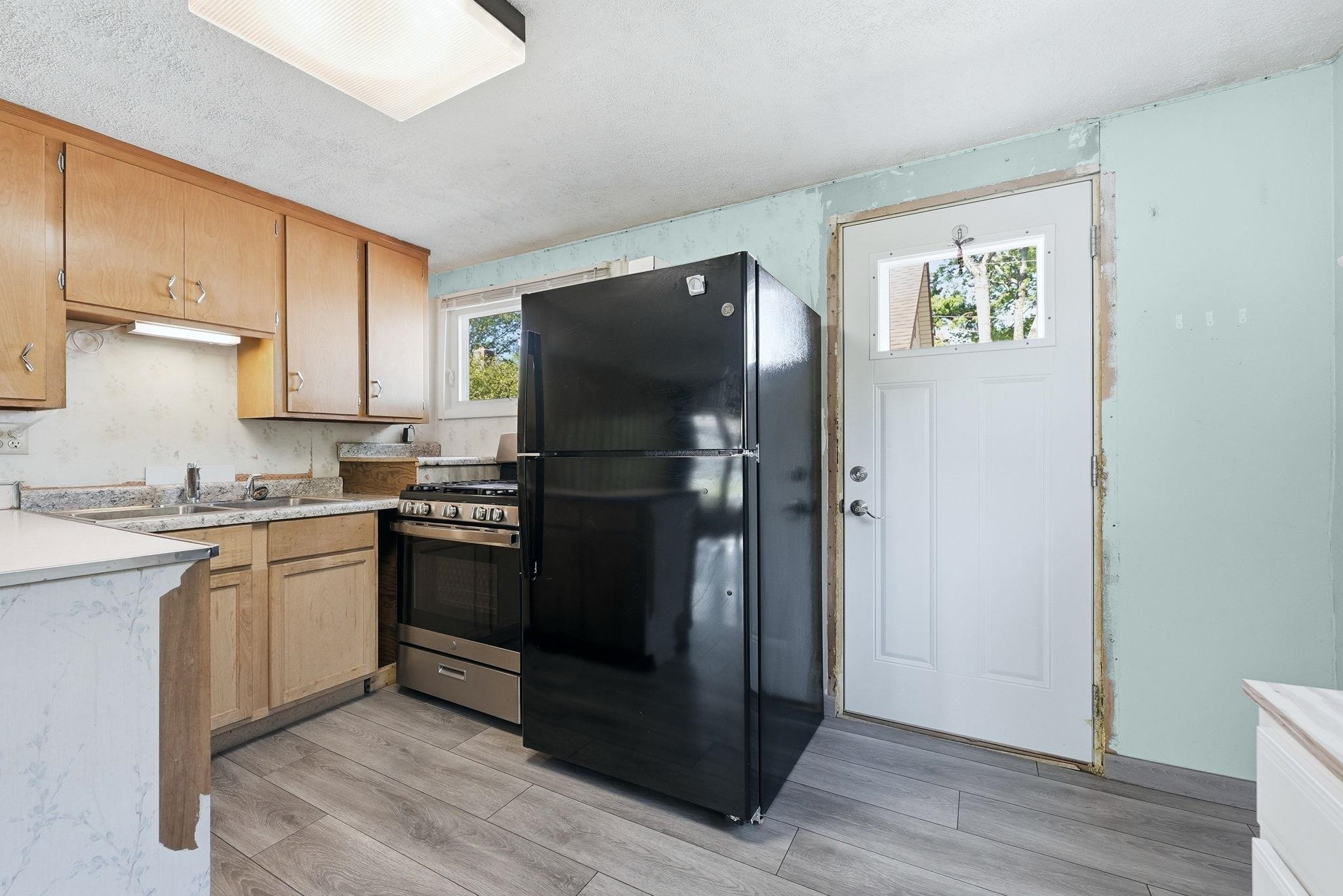 Kitchen area featuring wood-finish cabinetry, light-toned countertops, a stainless steel range, and wood-finish flooring