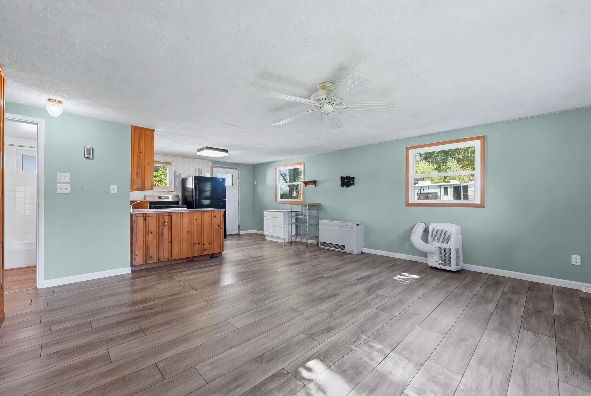 Open-concept living area with wood-finish flooring, a ceiling fan, and light blue wall tones