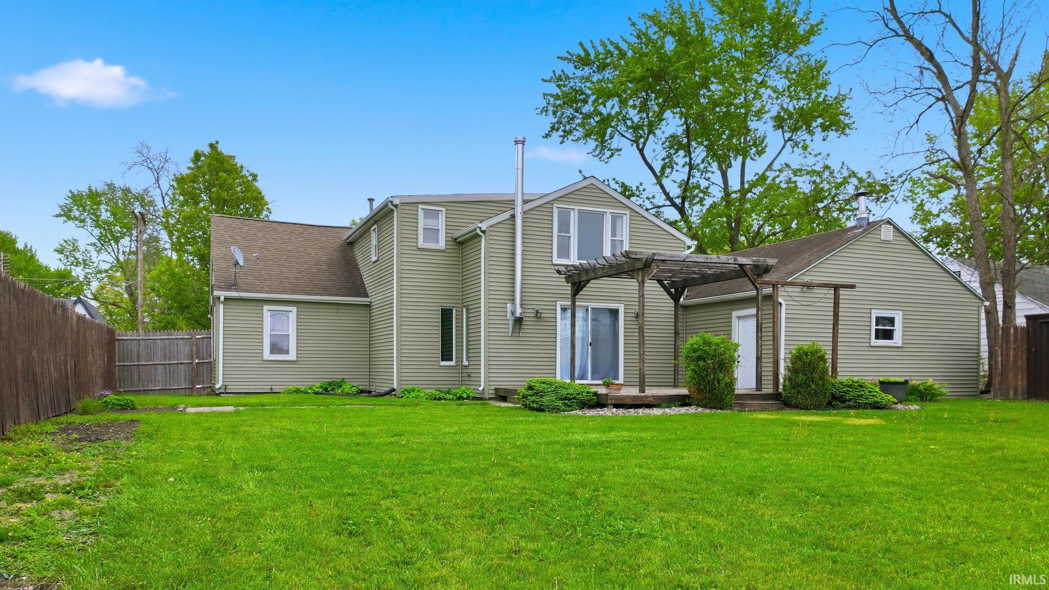 Expansive rear yard featuring green lawn and a wooden privacy fence