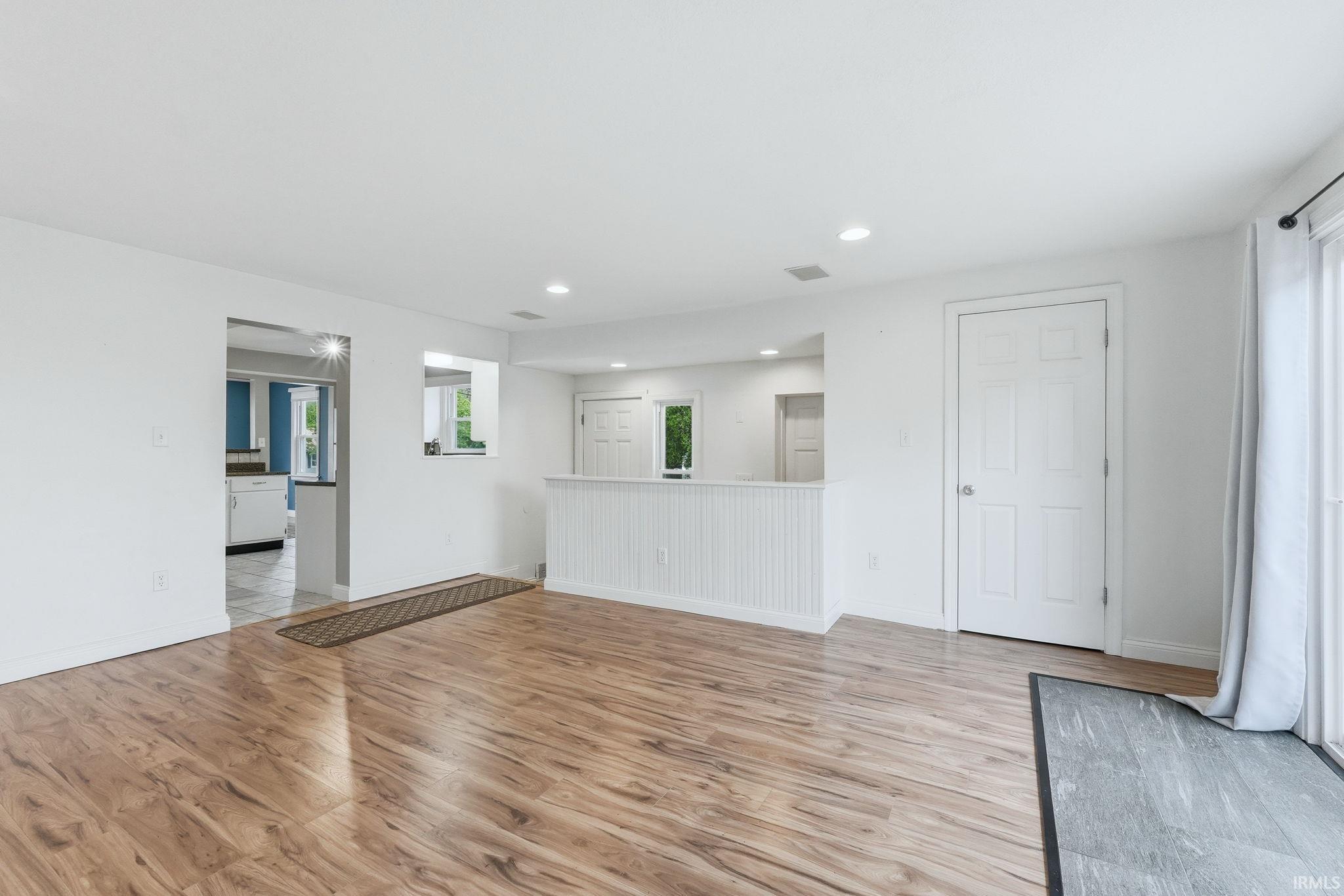 Spacious room featuring wood-finish flooring, recessed lighting, and white walls