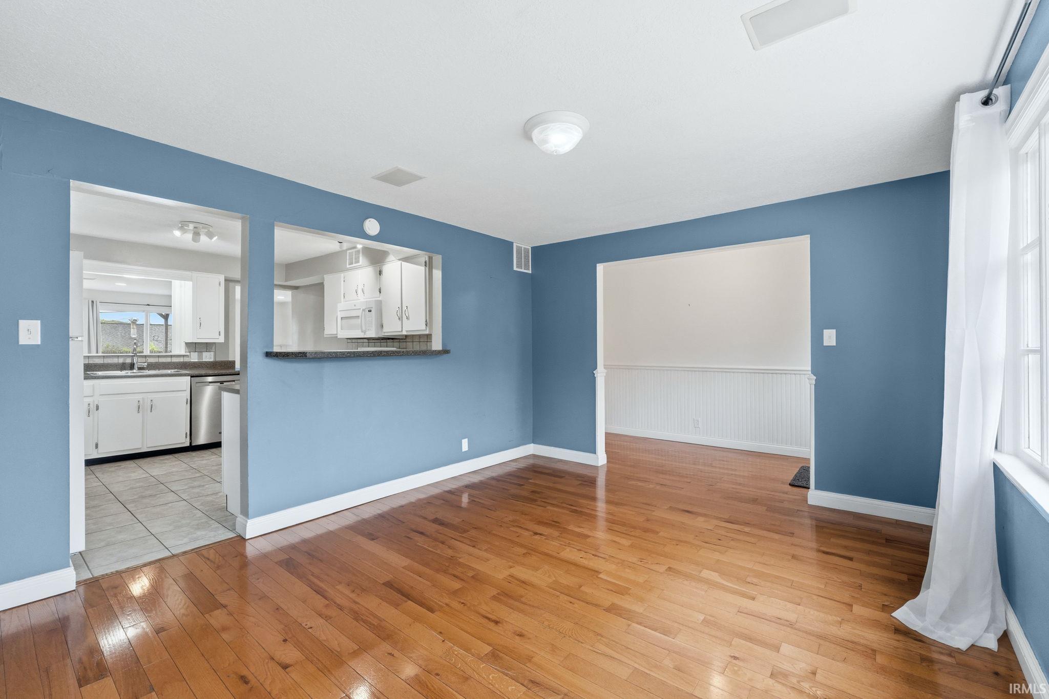 Open concept living space featuring wood-finish flooring and a pass-through window to the kitchen