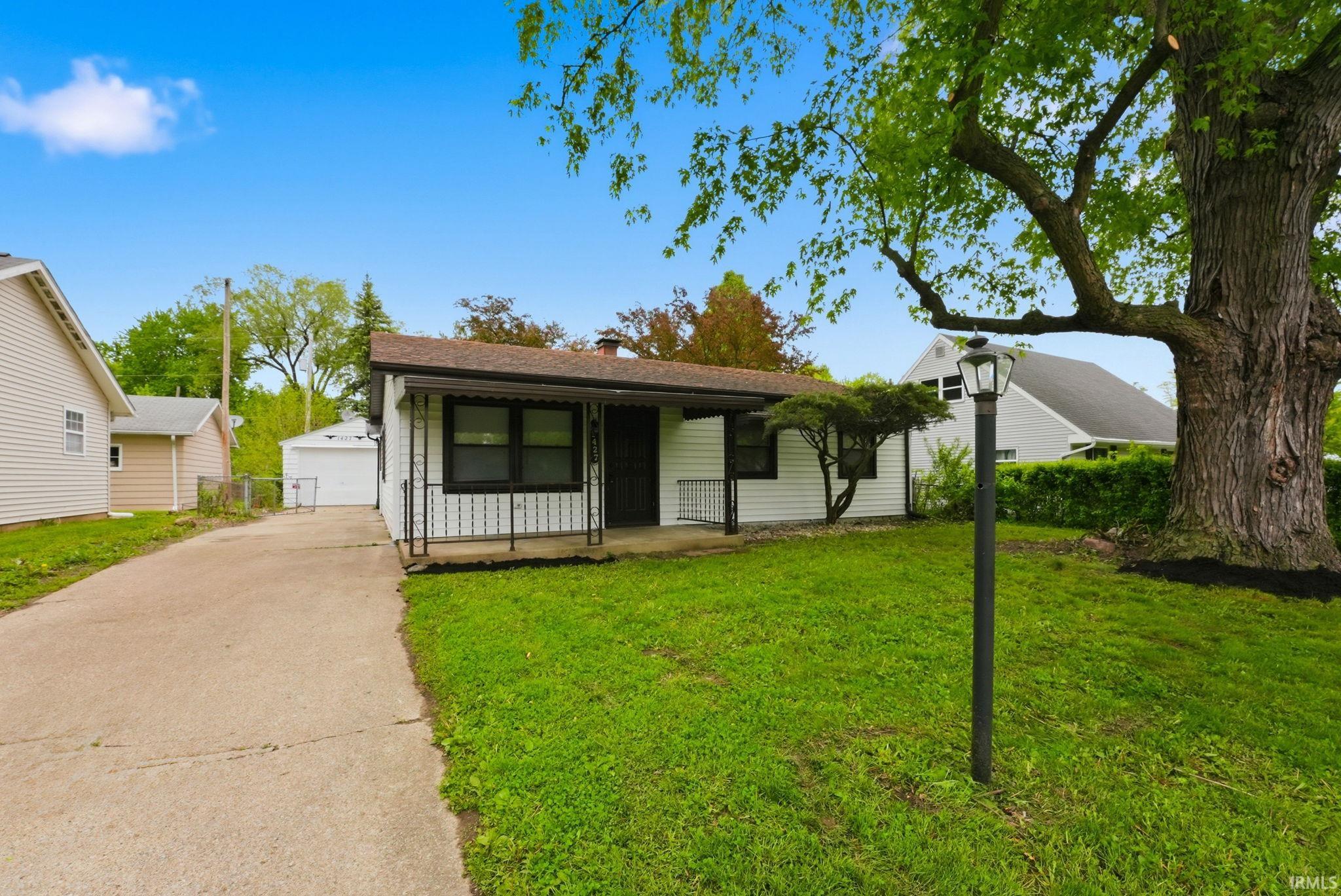 White siding exterior with black trim and a covered front porch featuring wrought iron railings