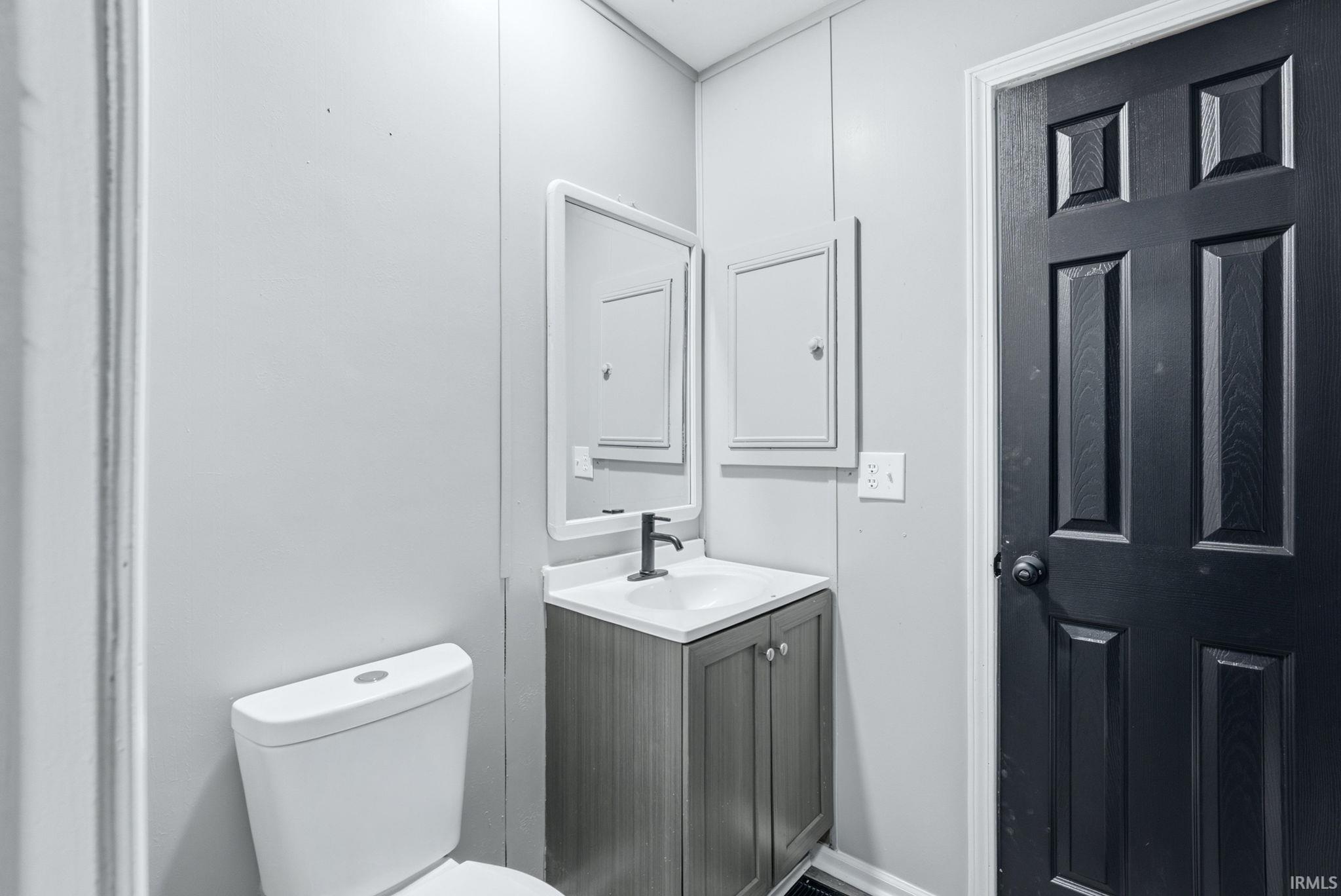 Bathroom vanity featuring a white rectangular sink with a matte black faucet, set against a light gray wall