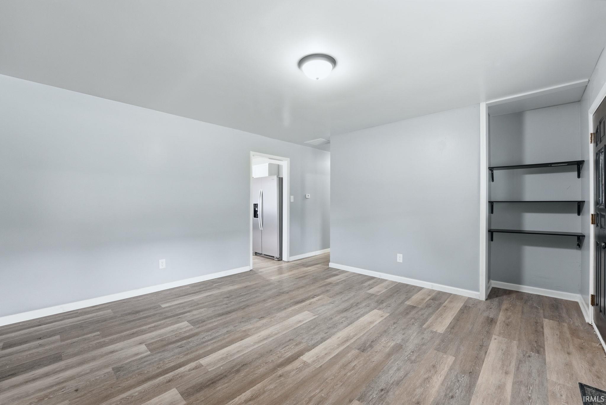 Living area featuring wide plank wood-finish flooring, light gray walls, white baseboards, and a semi-flush mount ceiling light