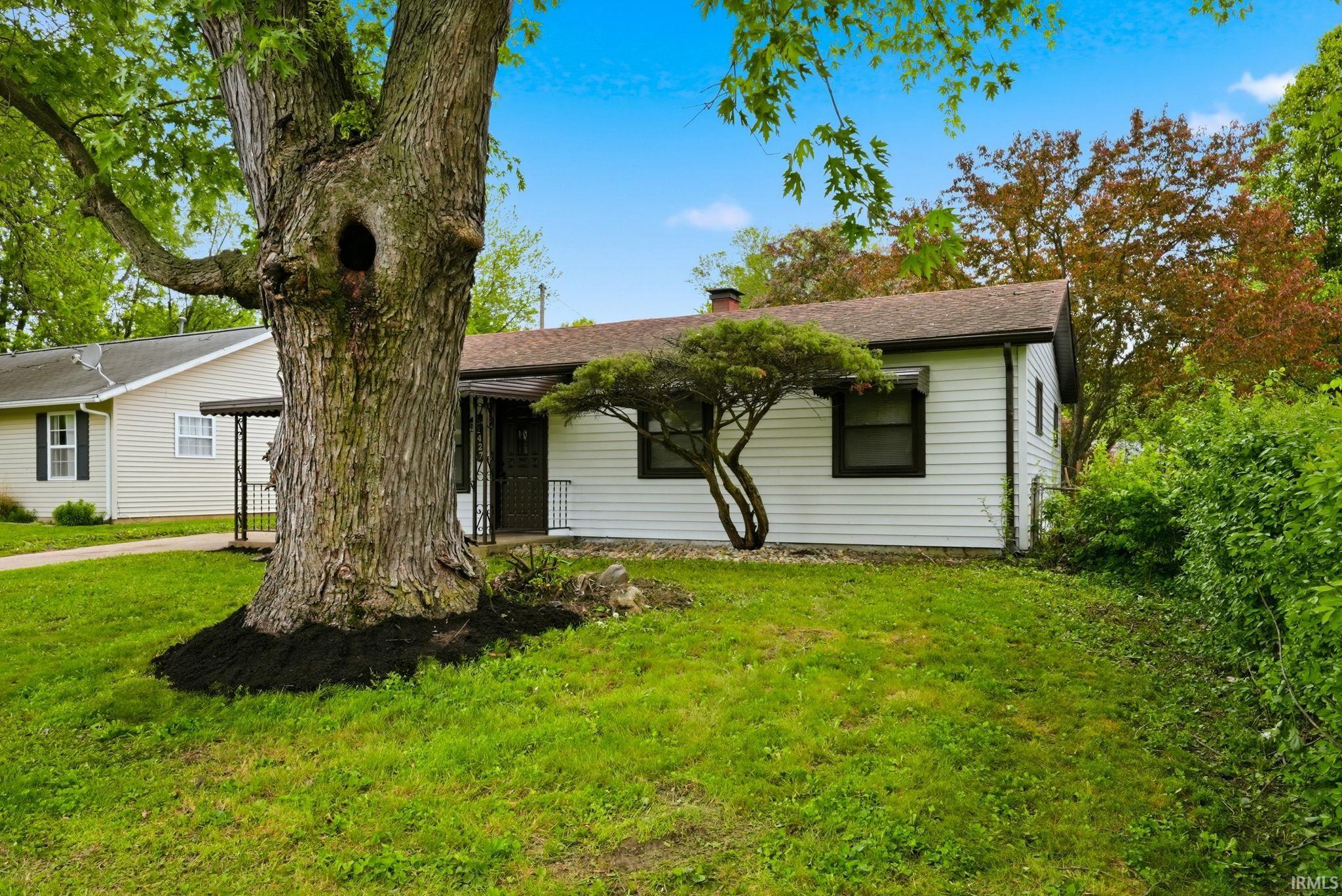 Single-story residence featuring white siding, a brown roof, and dark trim