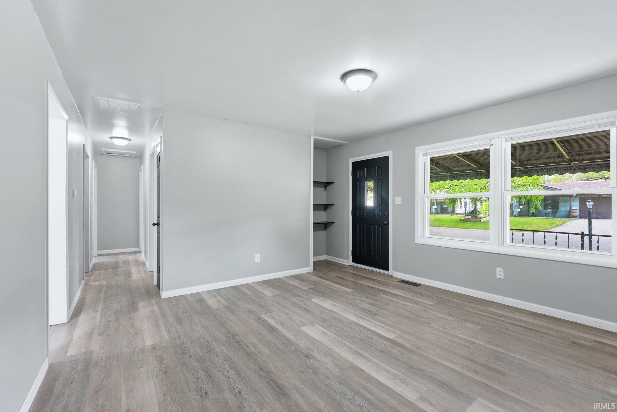 Bright interior space featuring wood-finish flooring, light gray wall paint, and white baseboards