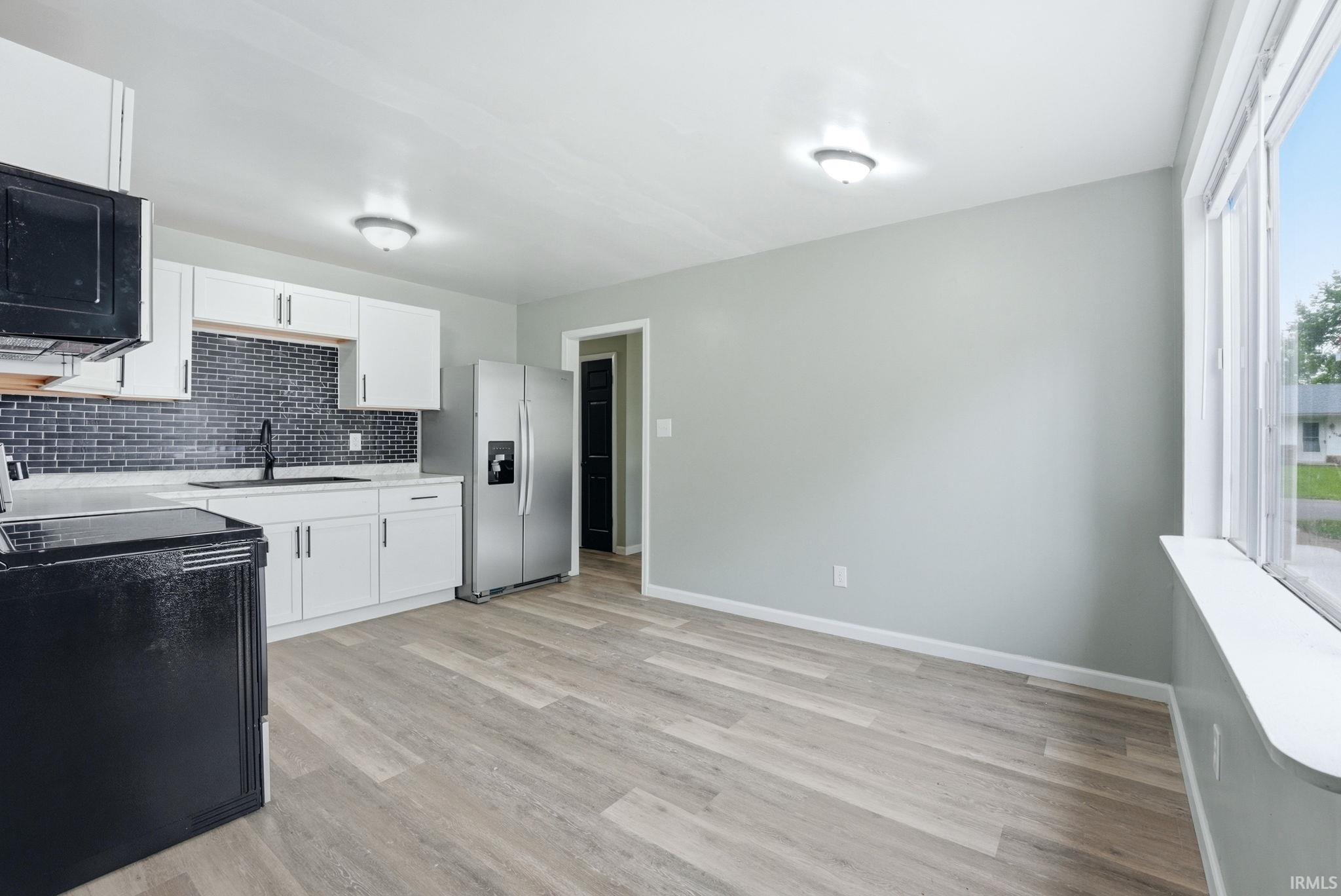 Open-concept kitchen and dining area featuring light wood-finish flooring