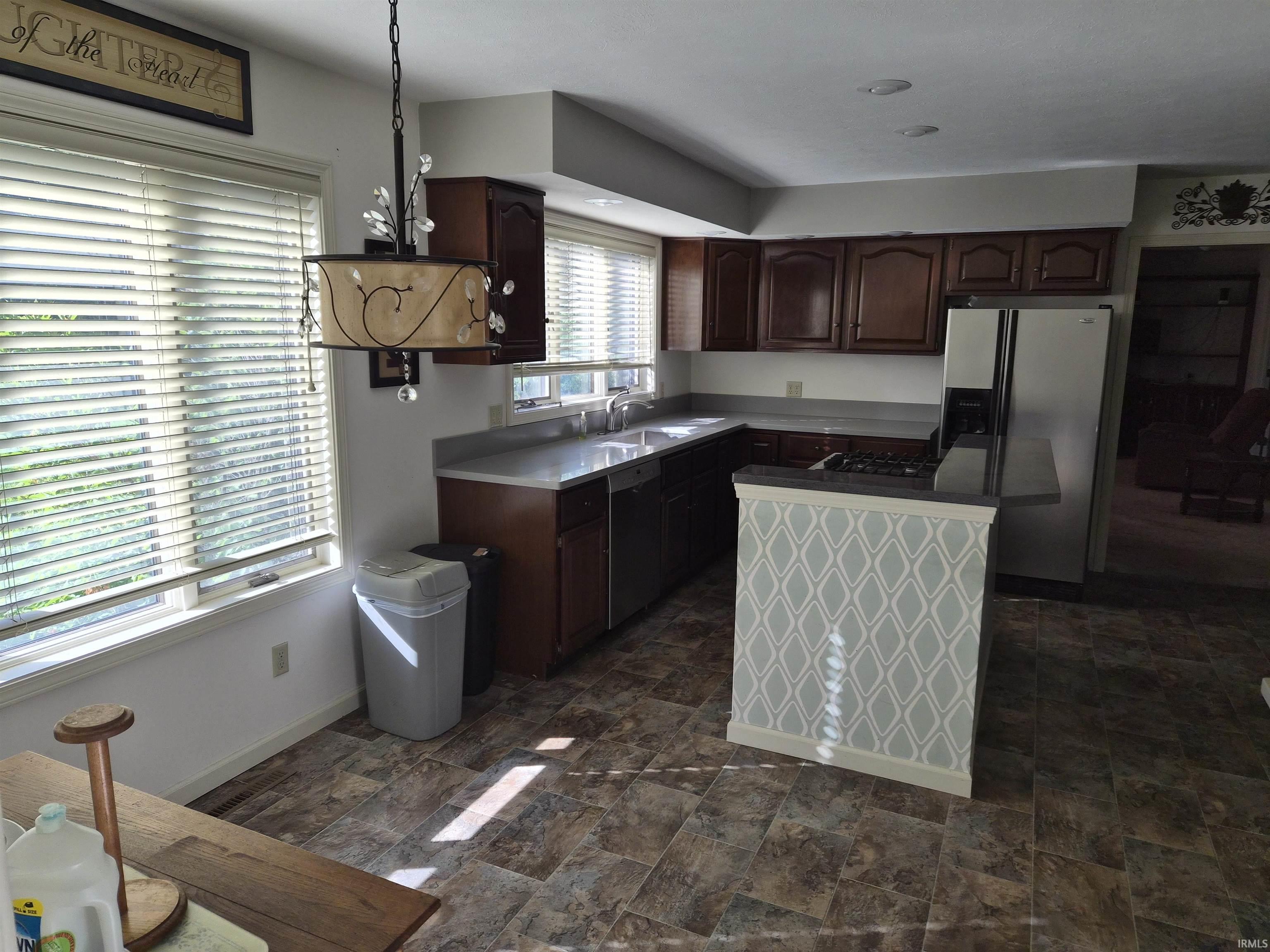 Kitchen featuring dark wood cabinetry, gray countertops, and a double basin sink