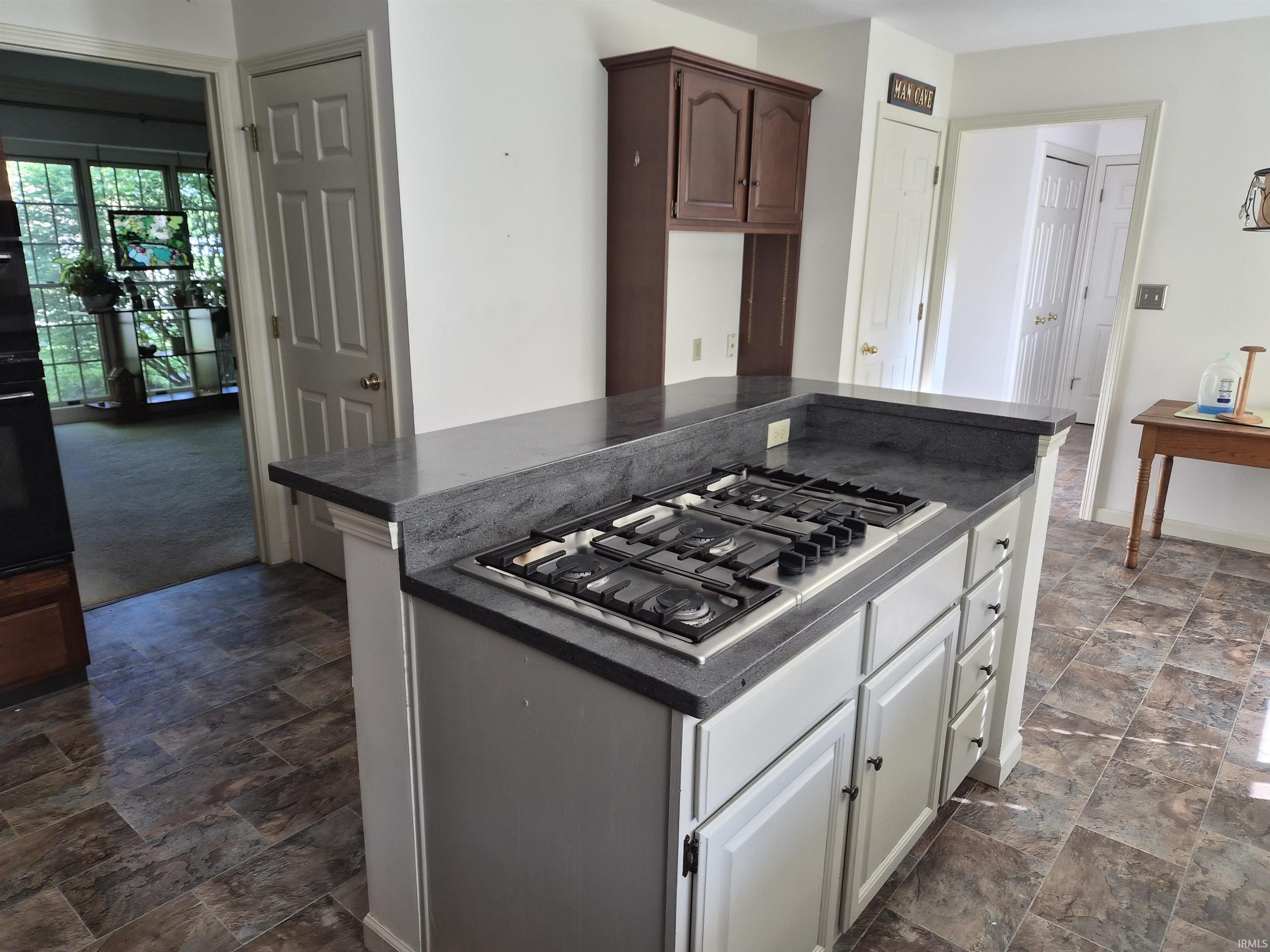 Kitchen island featuring a four-burner gas cooktop, gray solid-surface countertops, and white cabinetry