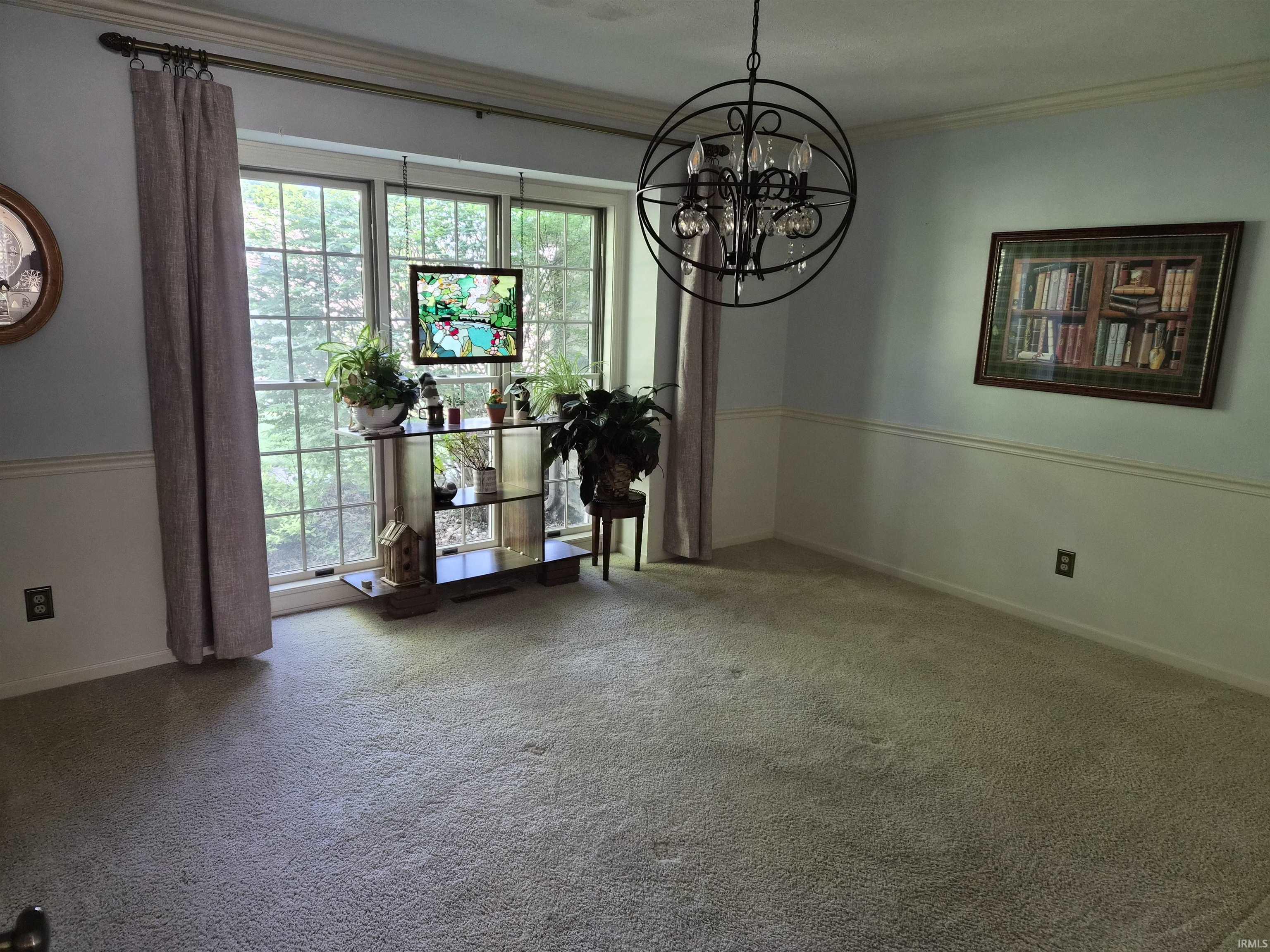 Formal room featuring a large bay window, crown molding, chair rail molding, and a decorative chandelier