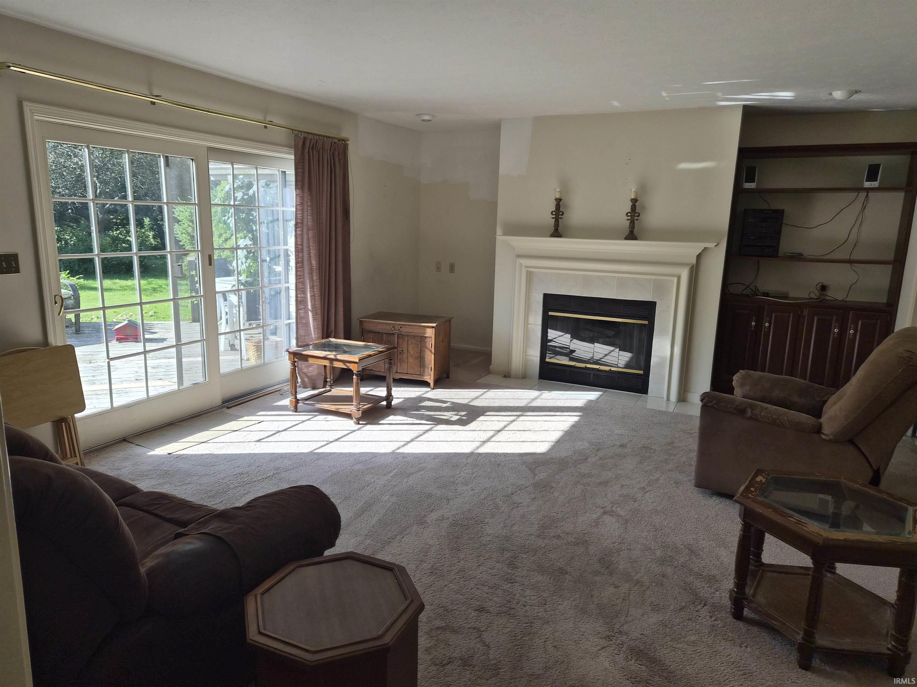 Living area featuring a fireplace with a mantel, built-in shelving, and sliding glass doors