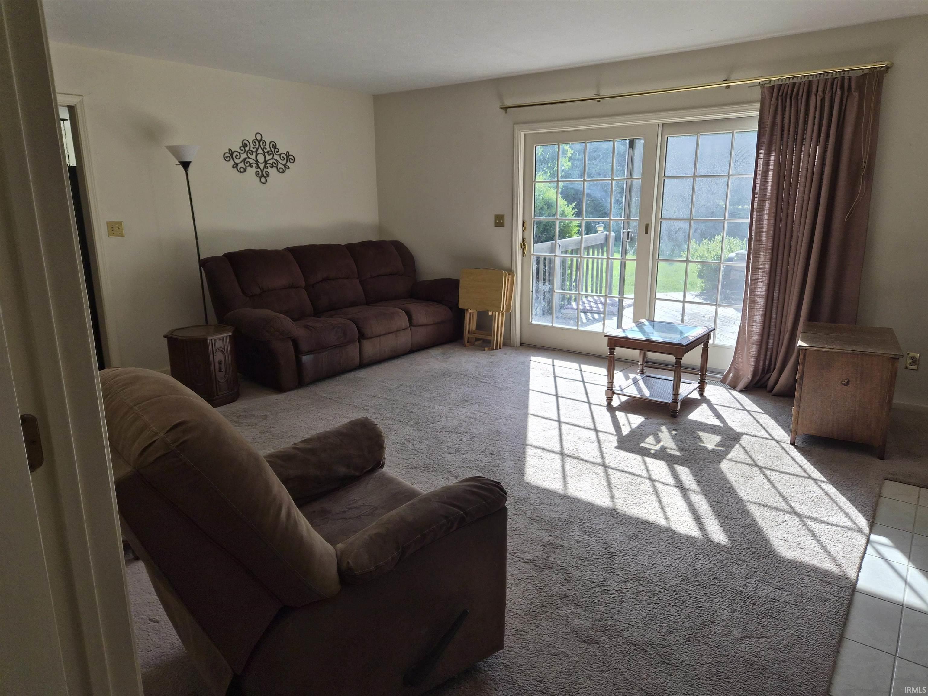 Sliding glass patio doors with grid detailing, neutral-toned carpeting, light-colored wall paint, and a white tile threshold