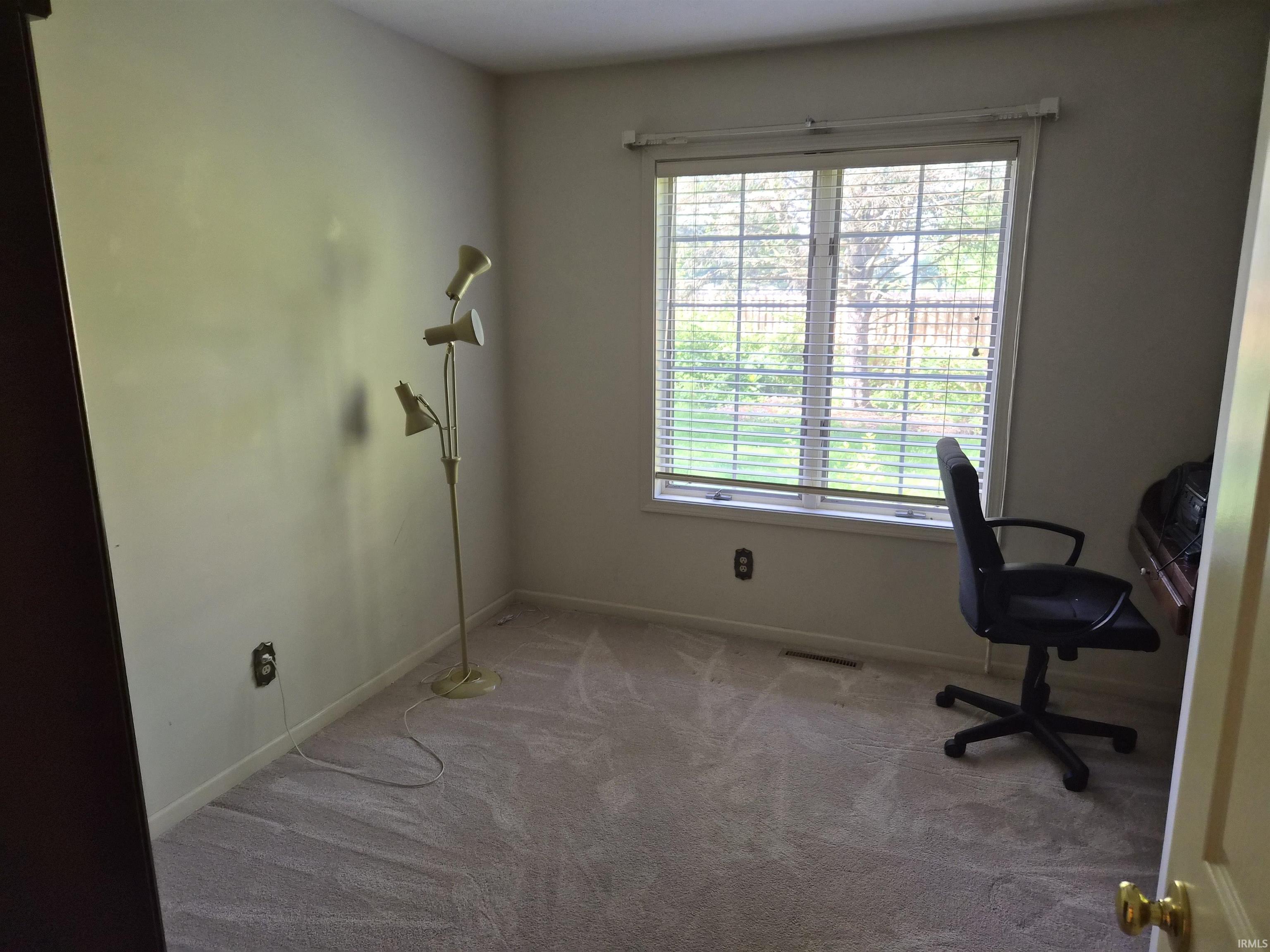 Neutral wall paint, plush carpet flooring, and a window with horizontal blinds