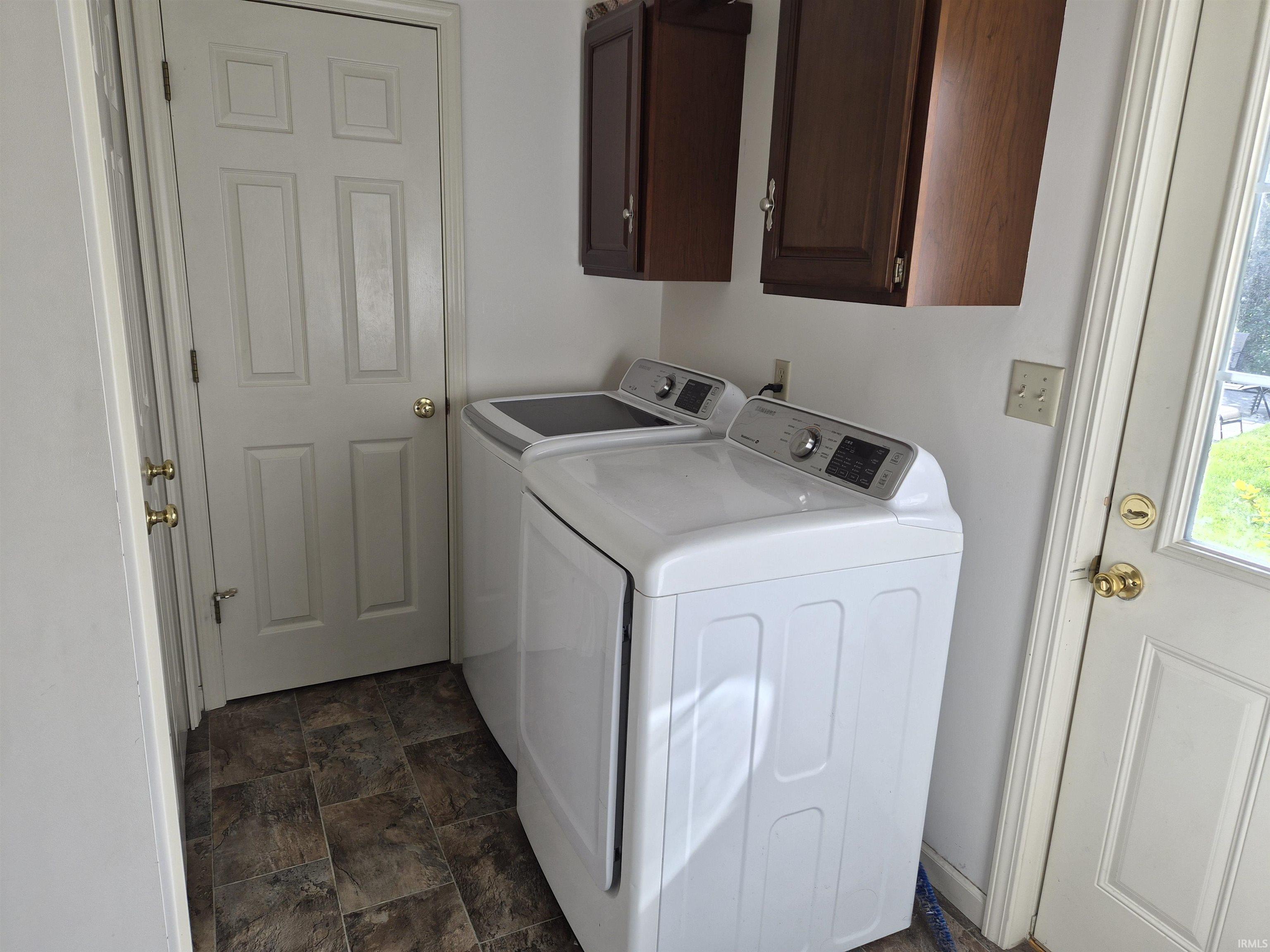 Laundry area featuring overhead cabinetry, panel doors, and tile-finish flooring