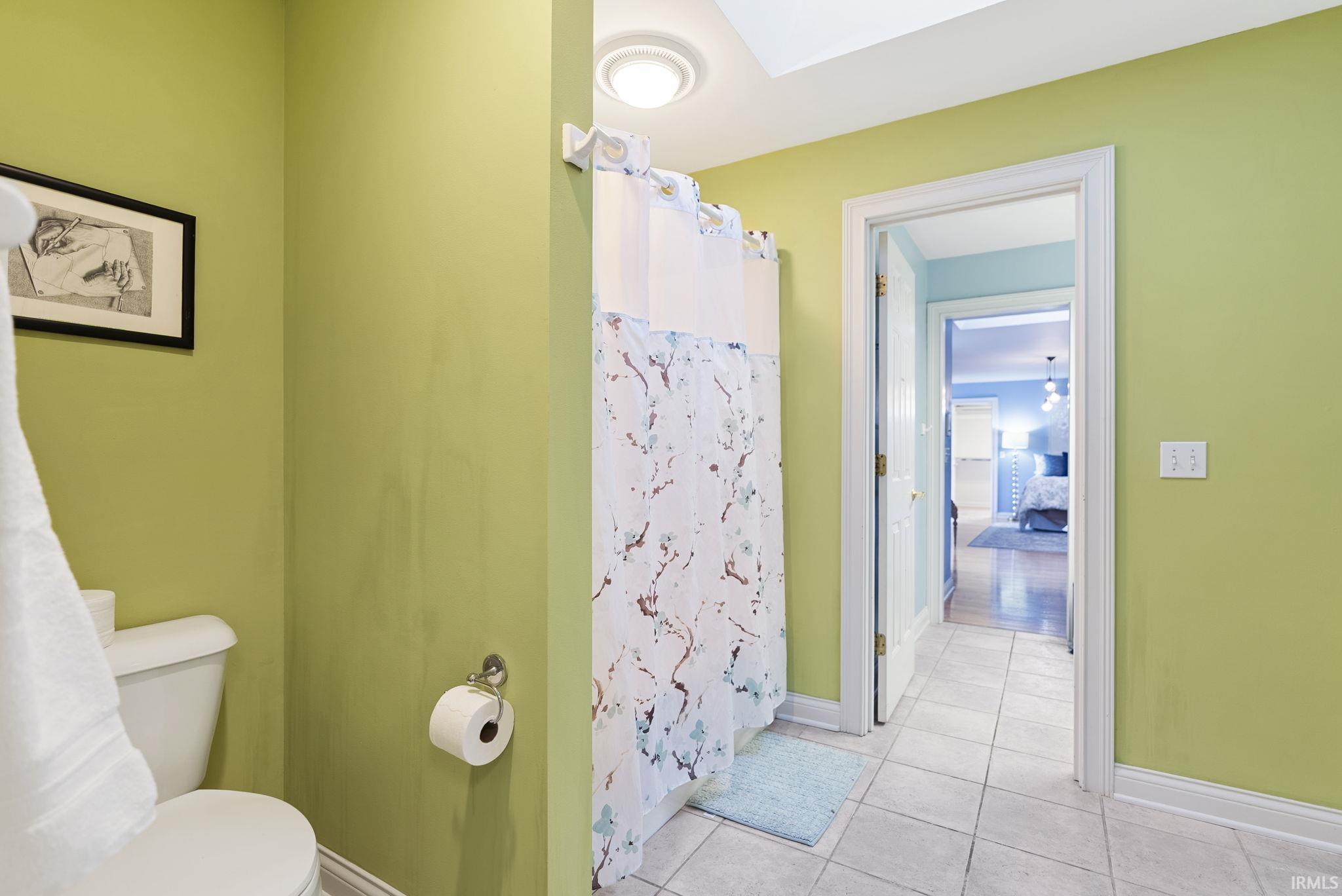 Bathroom with light green walls, white trim, and a tile floor