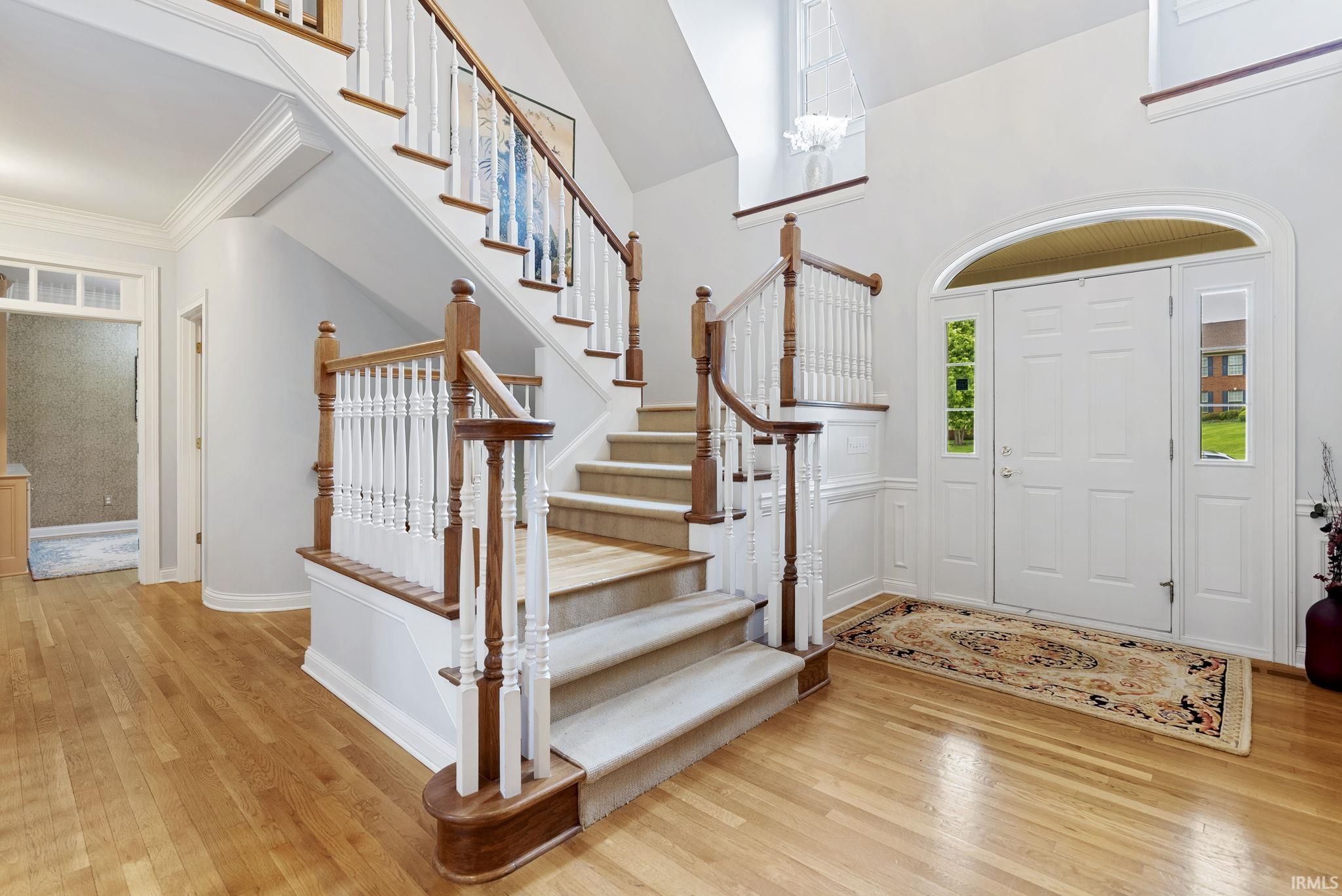 Grand foyer featuring a light wood-finish floor and a double-door entry with sidelights and an arched transom window