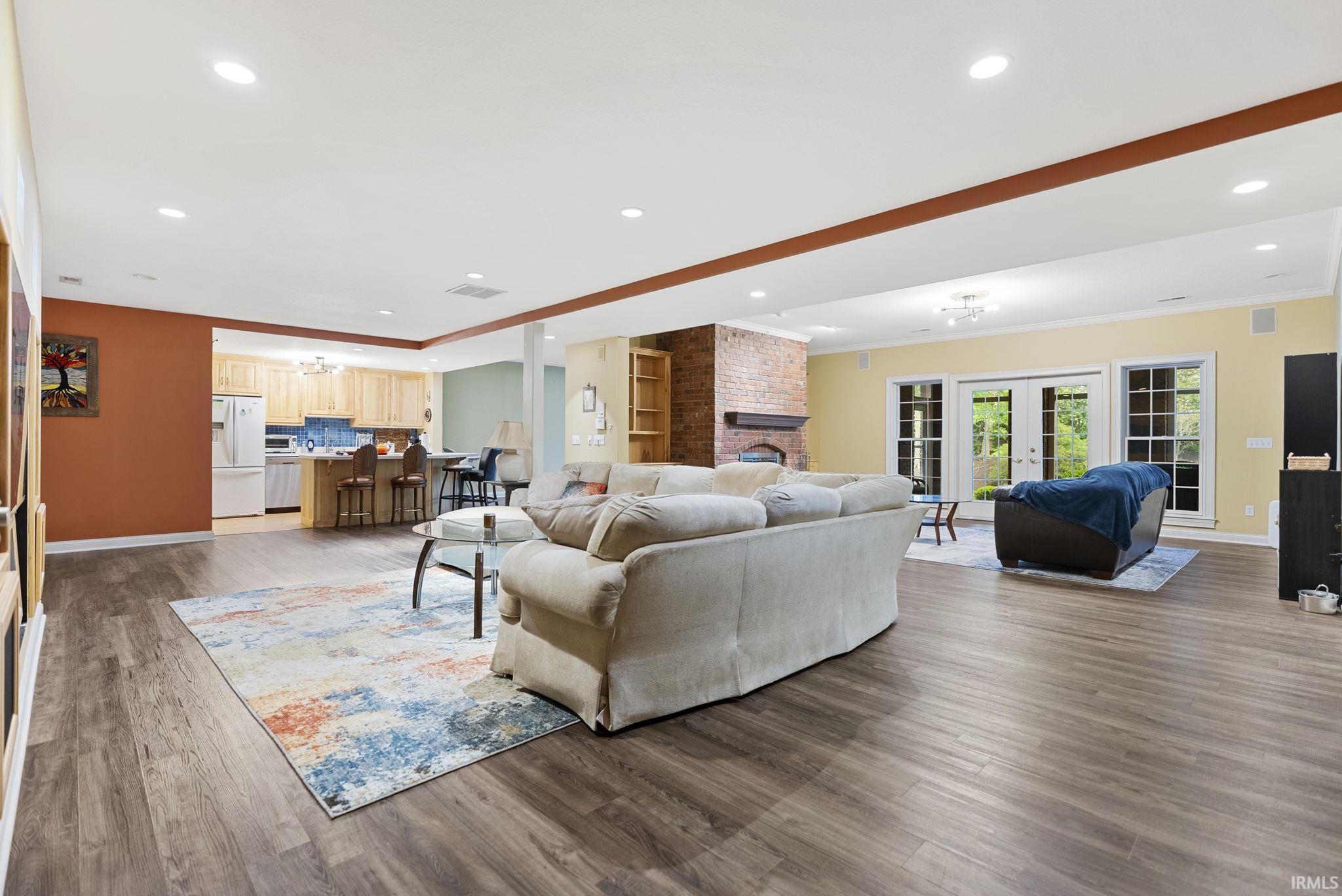 Open-concept living space featuring wood-finish flooring, recessed lighting, and a brick fireplace