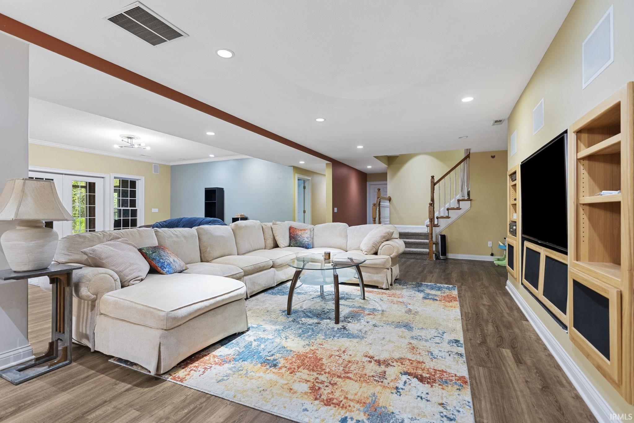 Spacious living area featuring wood-finish flooring, recessed lighting, and a built-in media center with shelving