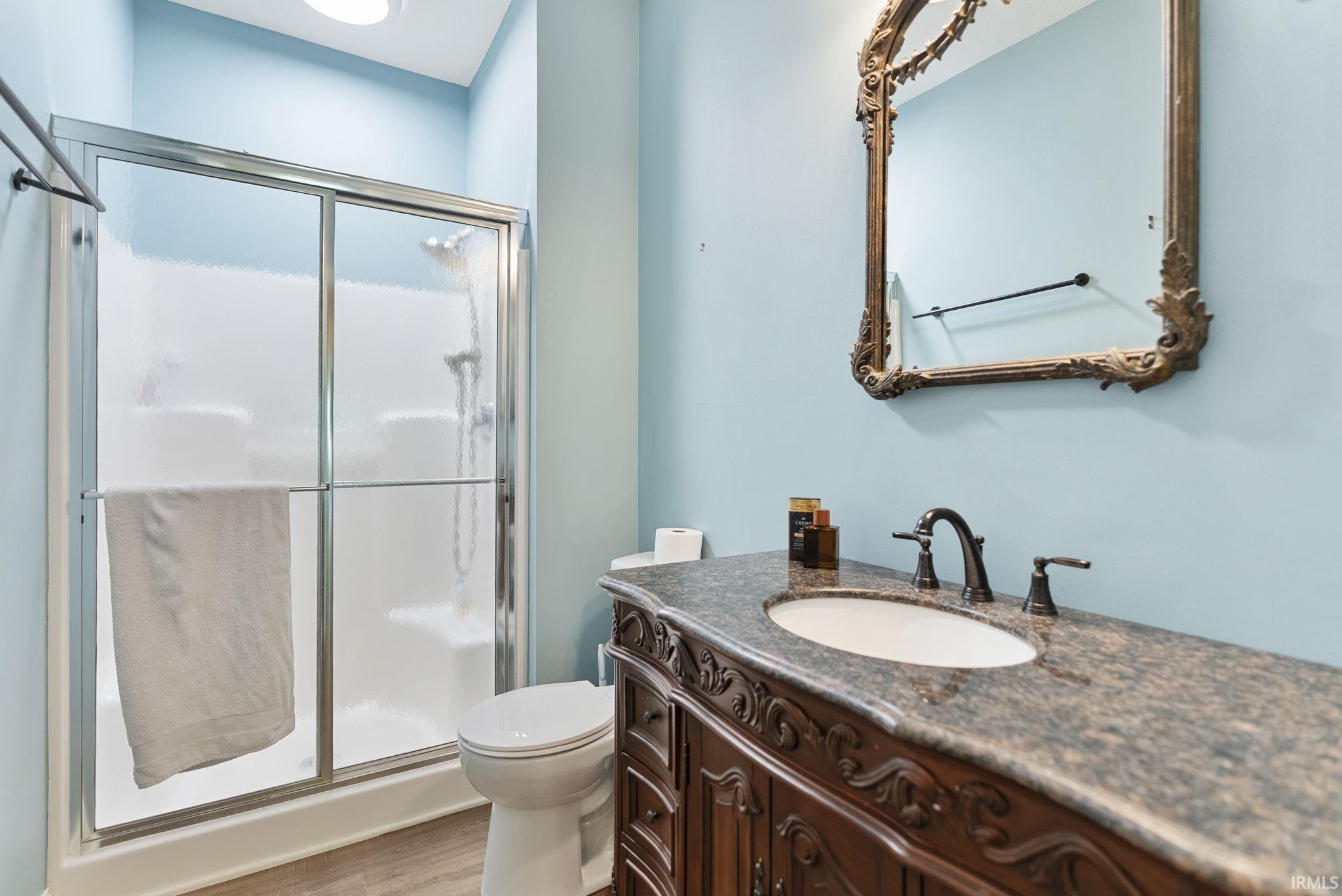 Bathroom featuring a full shower with sliding glass doors, a vanity with an integrated sink, a dark stone-finish countertop, and decorative wood-finish cabinetry with carved detailing