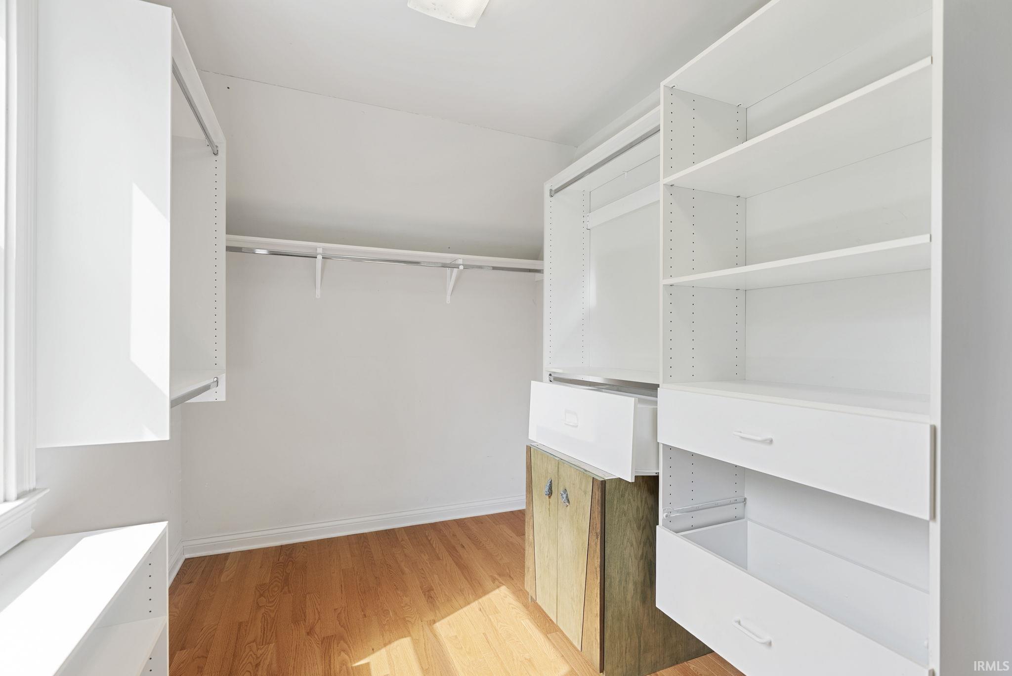 Walk-in closet featuring light wood-finish flooring