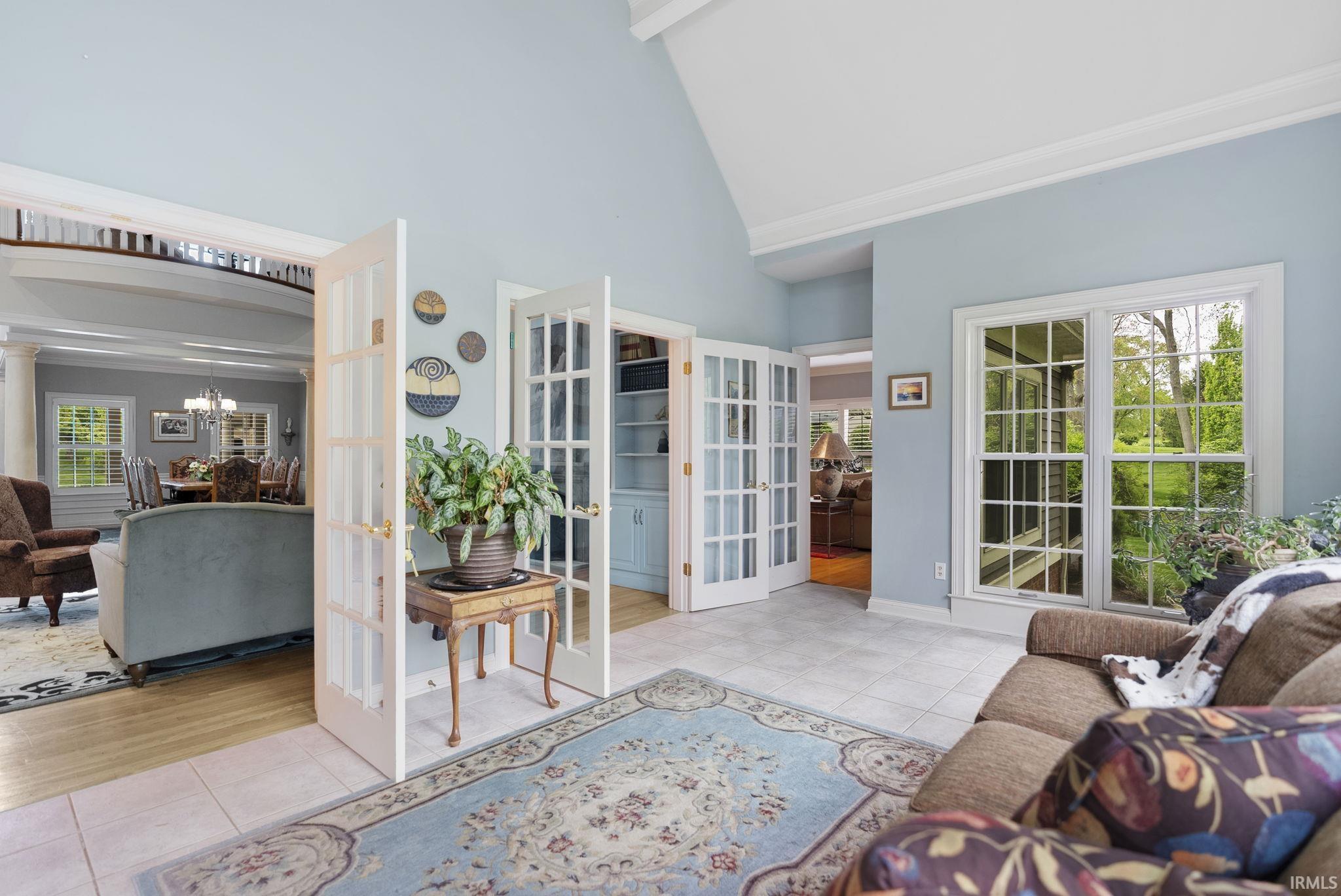 Spacious interior with vaulted ceilings, grid-pane windows, light blue walls, and tile flooring