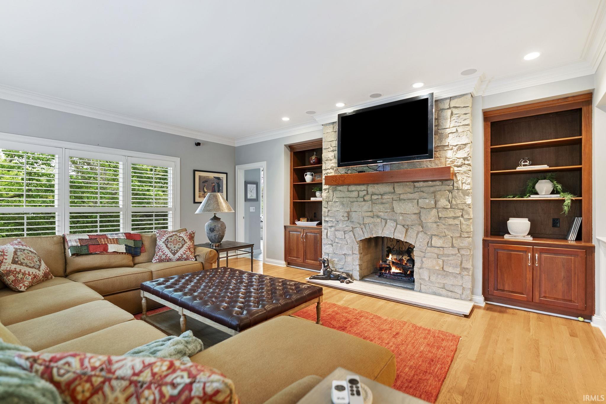 Living area featuring a stone-clad fireplace with hearth, a wood mantel, and built-in shelving with lower cabinetry
