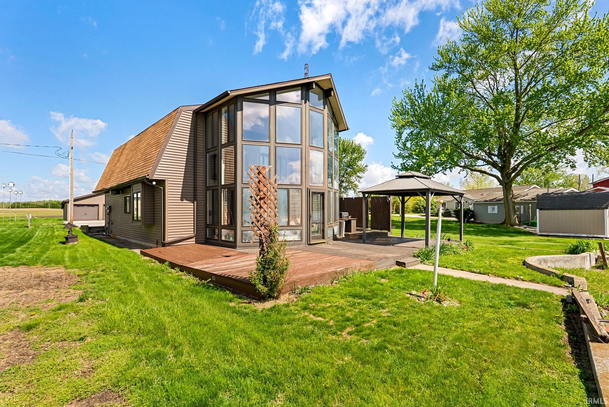 Barn-style residence featuring a multi-story glass facade, a wood-finish deck, and a detached two-car garage