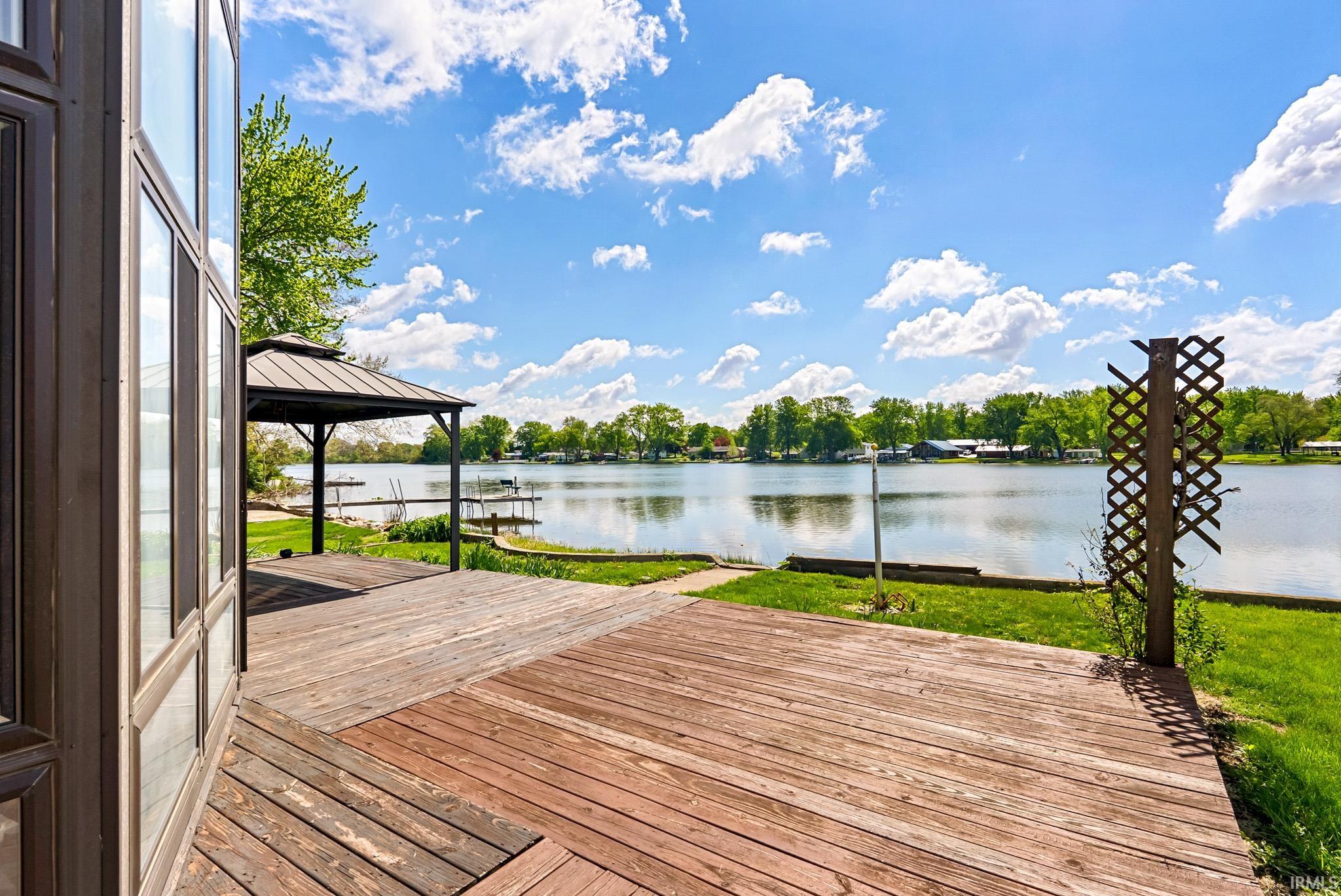 Expansive wood deck with a built-in gazebo, overlooking a serene body of water