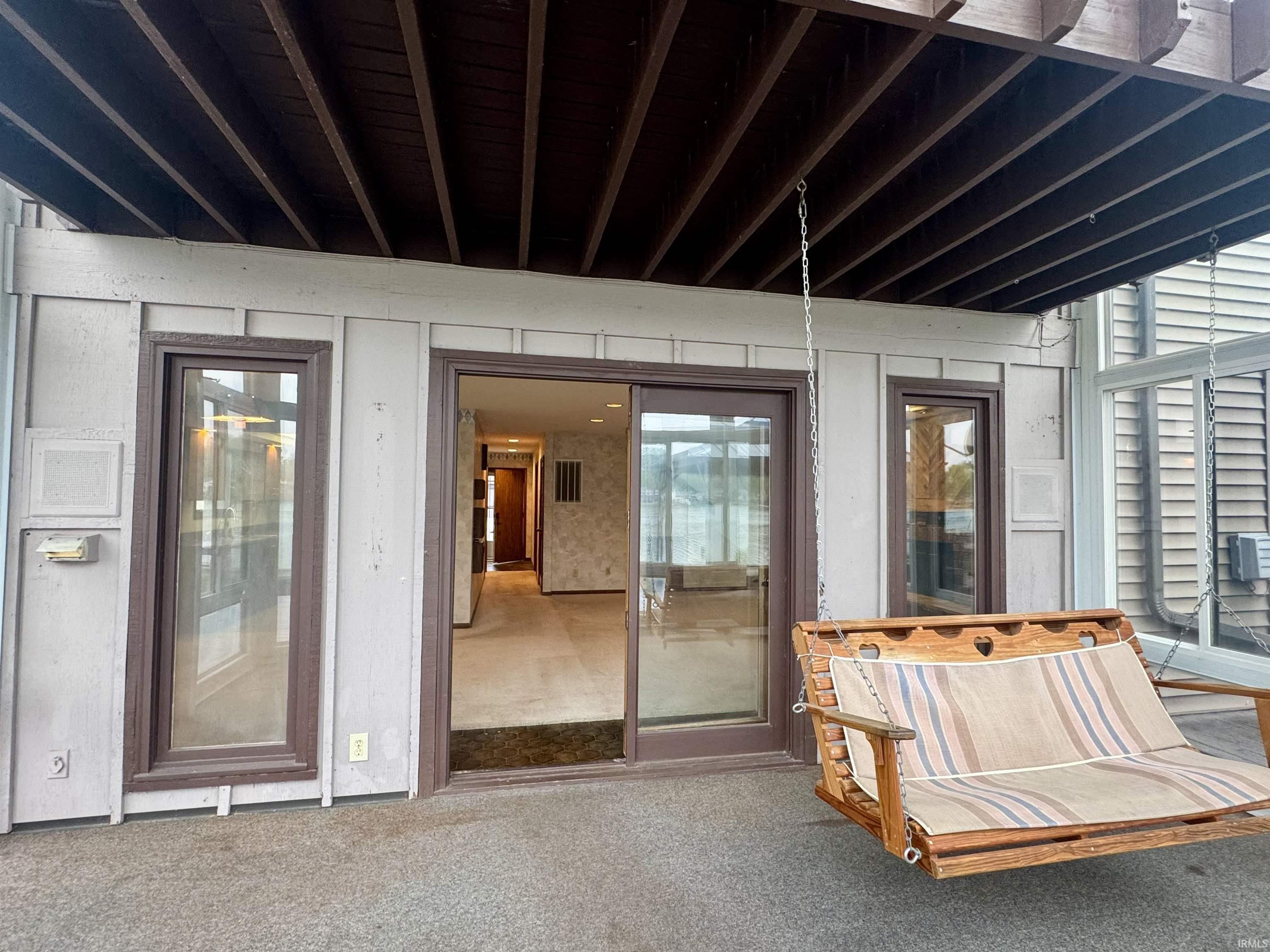 Covered outdoor patio area featuring a textured floor surface and a dark-stained wood slat ceiling