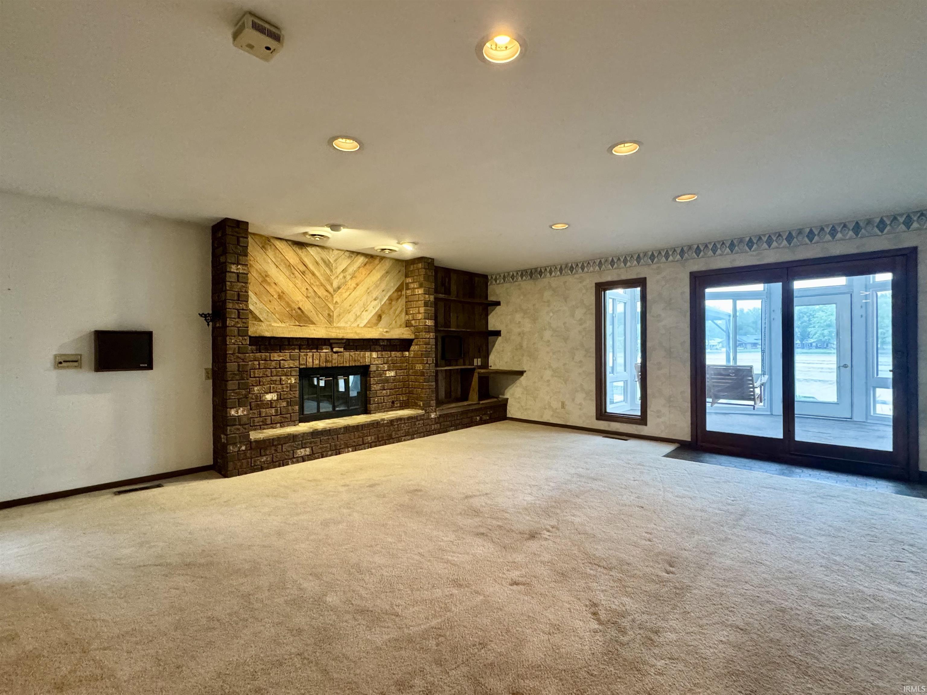 Spacious interior featuring a brick fireplace with a wood mantle and plank accent wall
