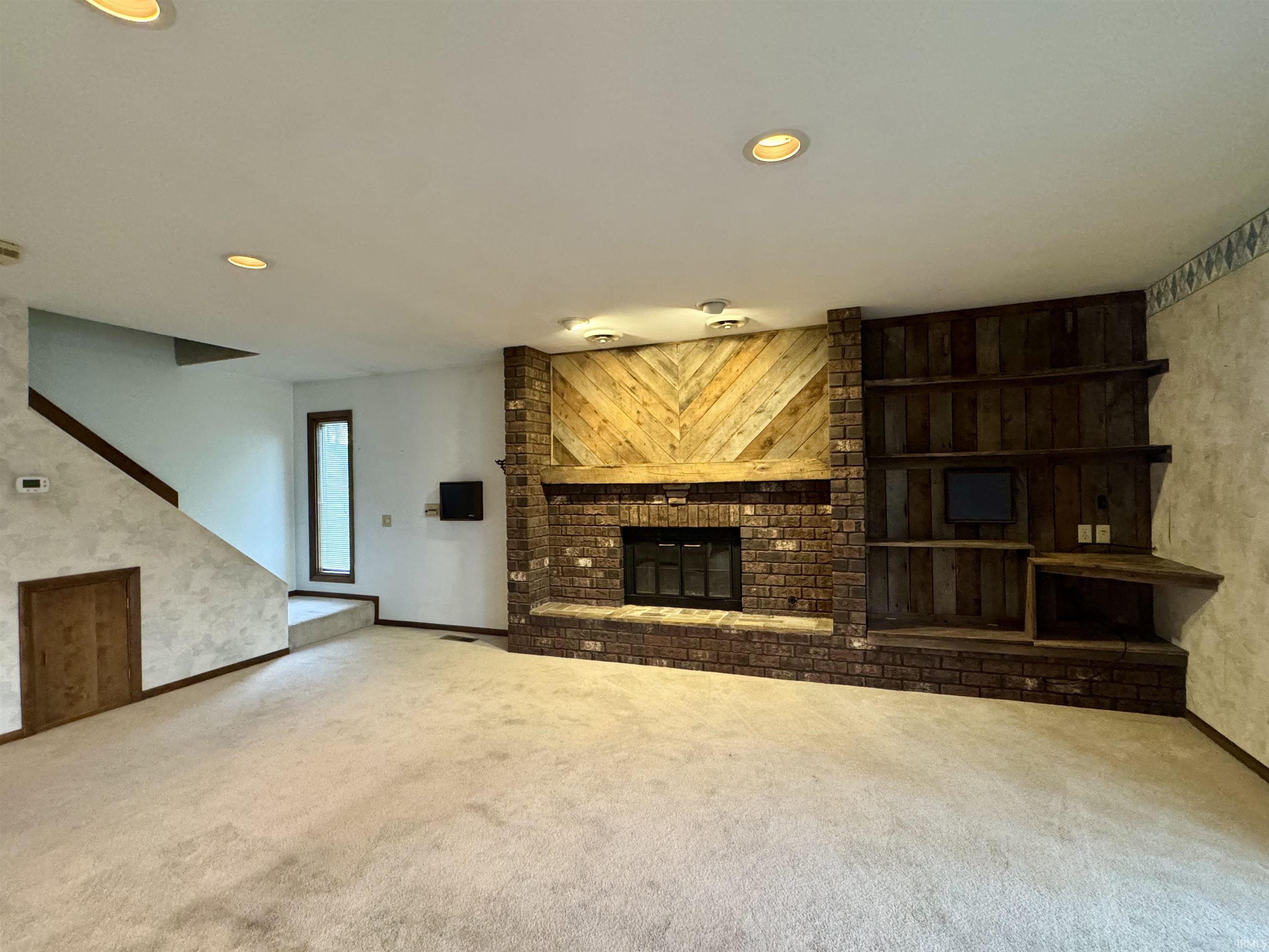 Brick fireplace with a wood mantle and integrated wood-paneled shelving