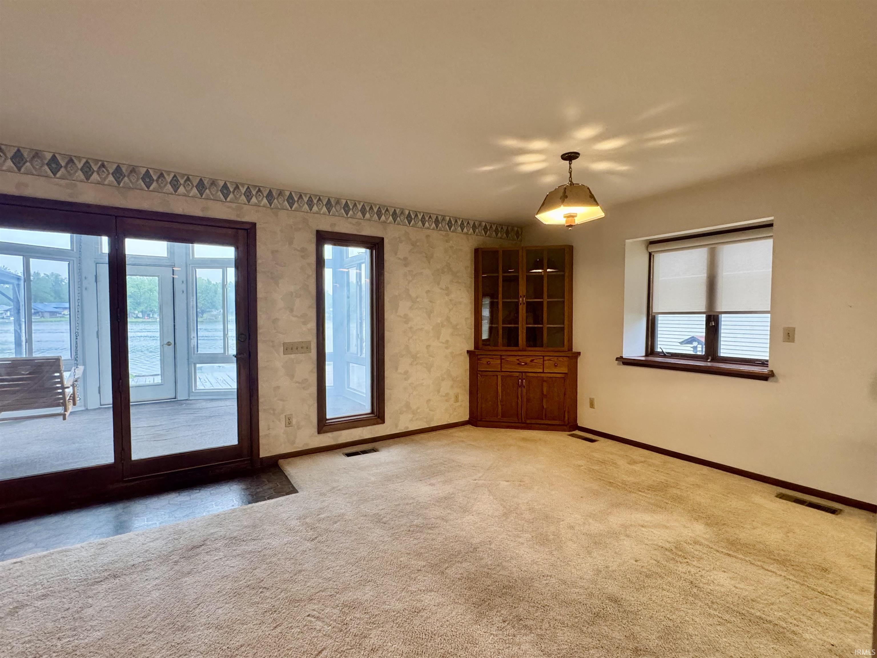 Carpeted interior space featuring a built-in corner cabinet, large glass sliding doors, and a window with blinds