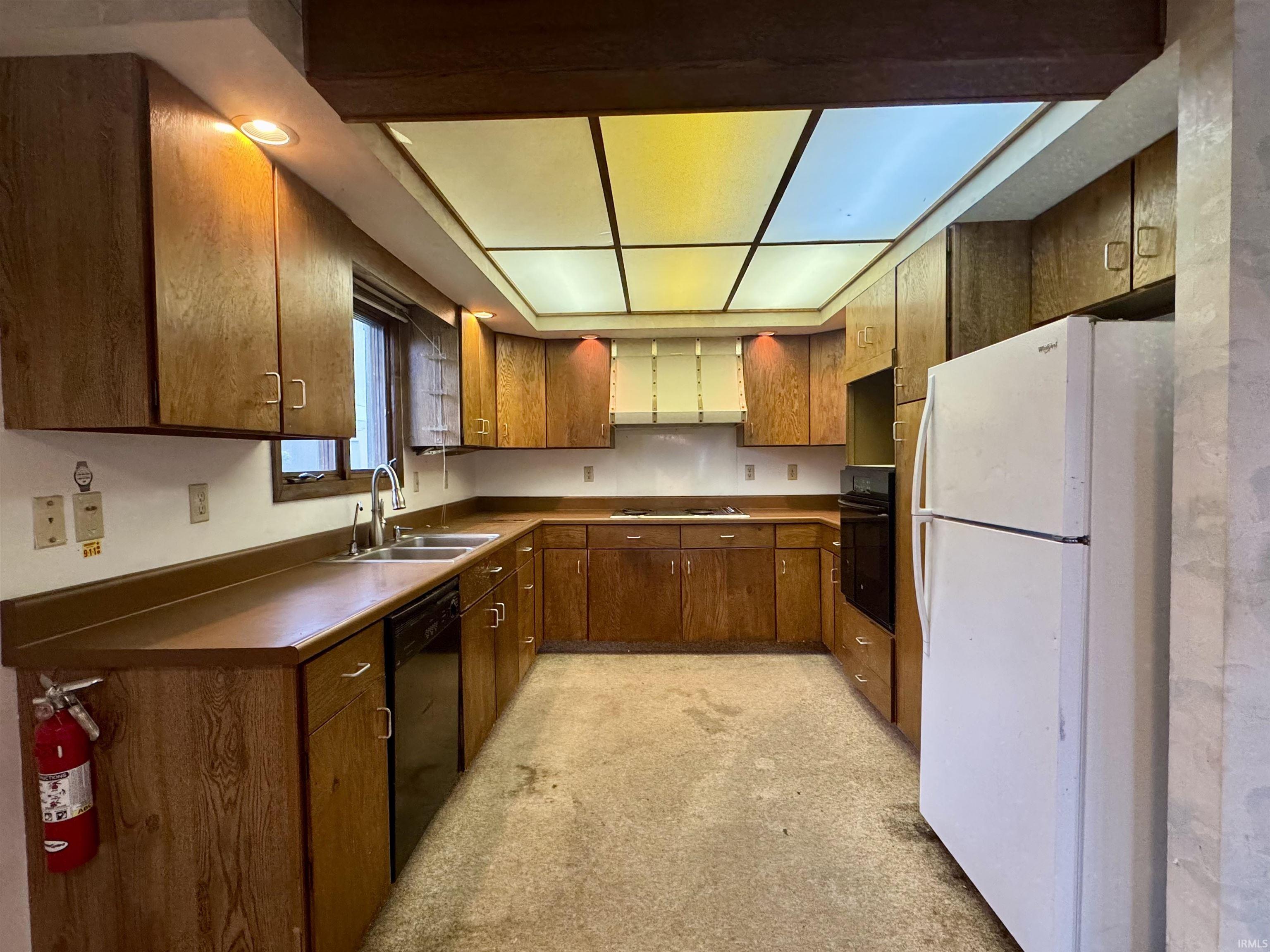 U-shaped kitchen layout with wood-finish cabinetry, a built-in oven, and a double basin sink