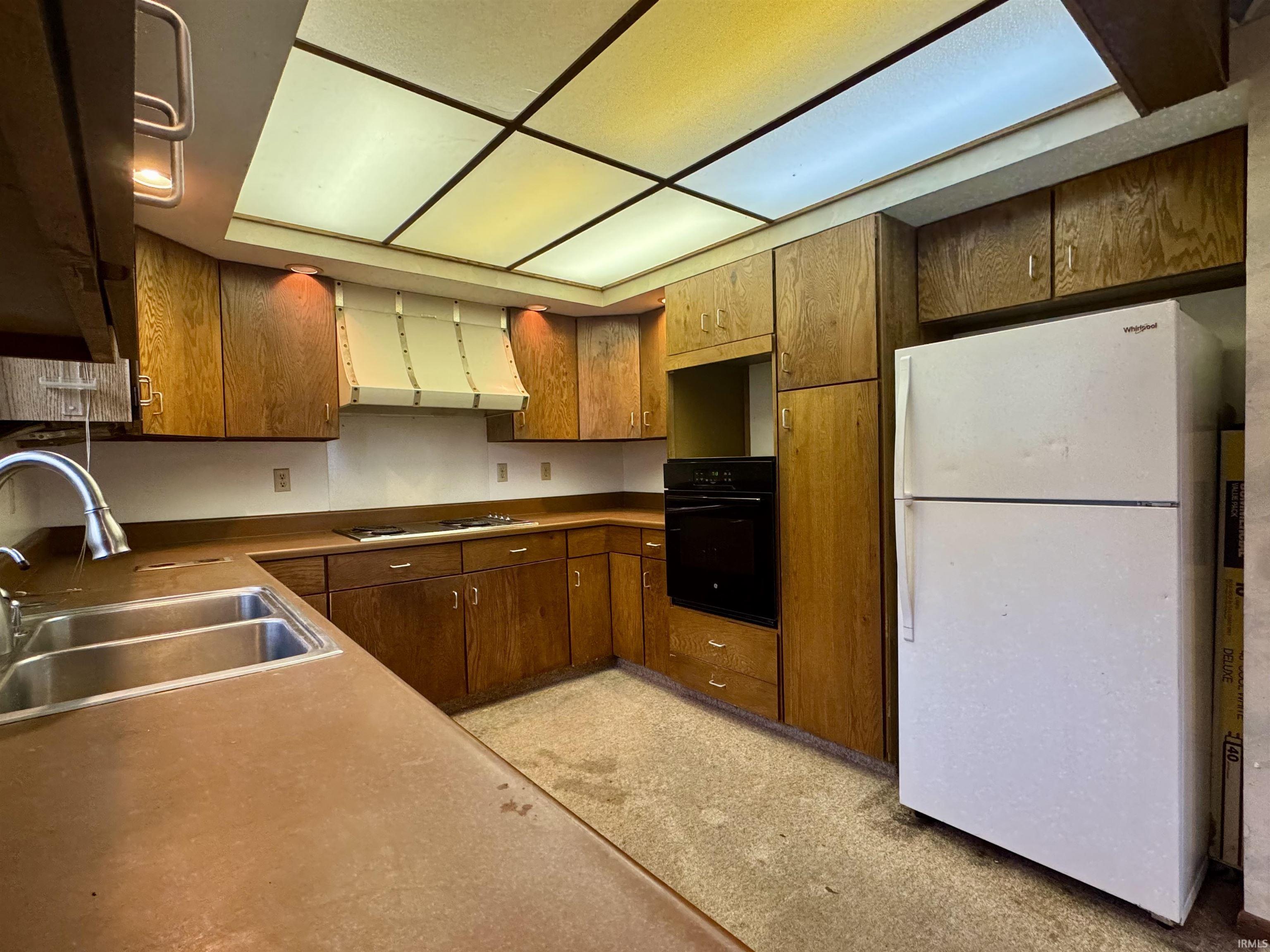 Kitchen featuring wood cabinetry, built-in oven, integrated cooktop, double basin sink, and recessed ceiling lighting
