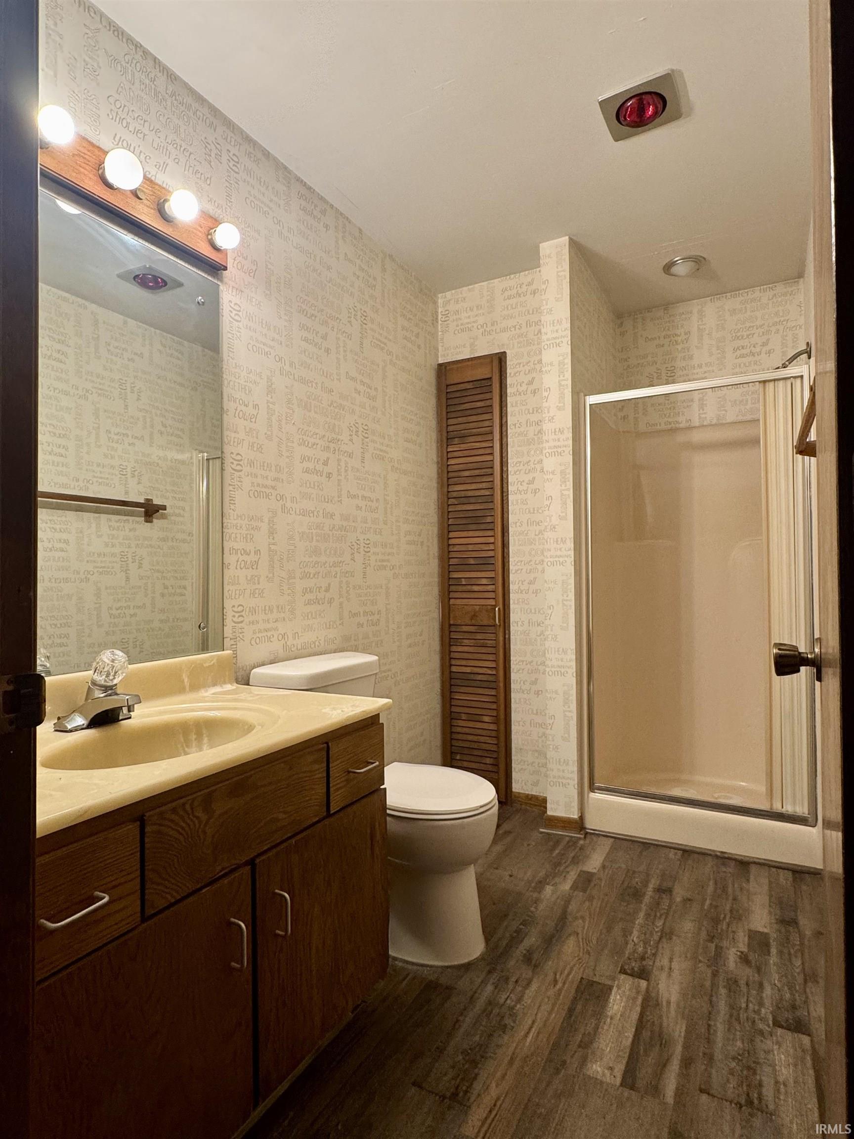 Bathroom featuring a wood-finish vanity with an integrated sink and a shower enclosure