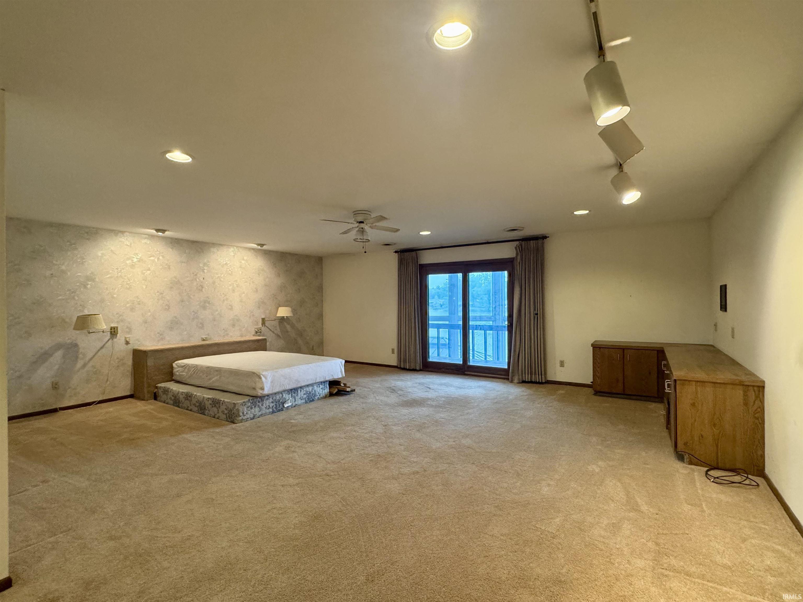 Spacious room featuring broadloom carpeting and a textured accent wall