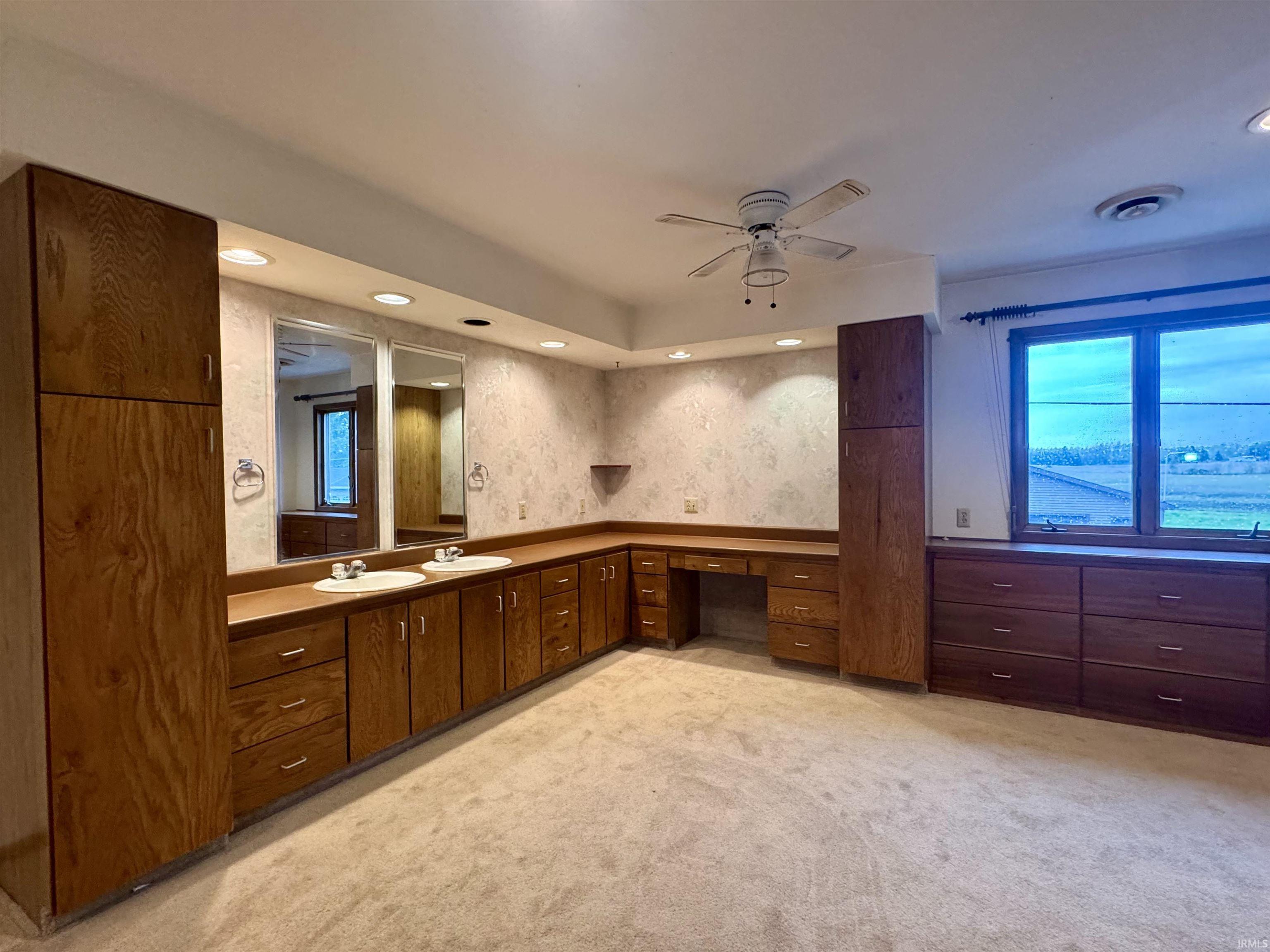 Spacious room featuring extensive wood cabinetry, dual vanity with integrated sinks, and ample countertop space