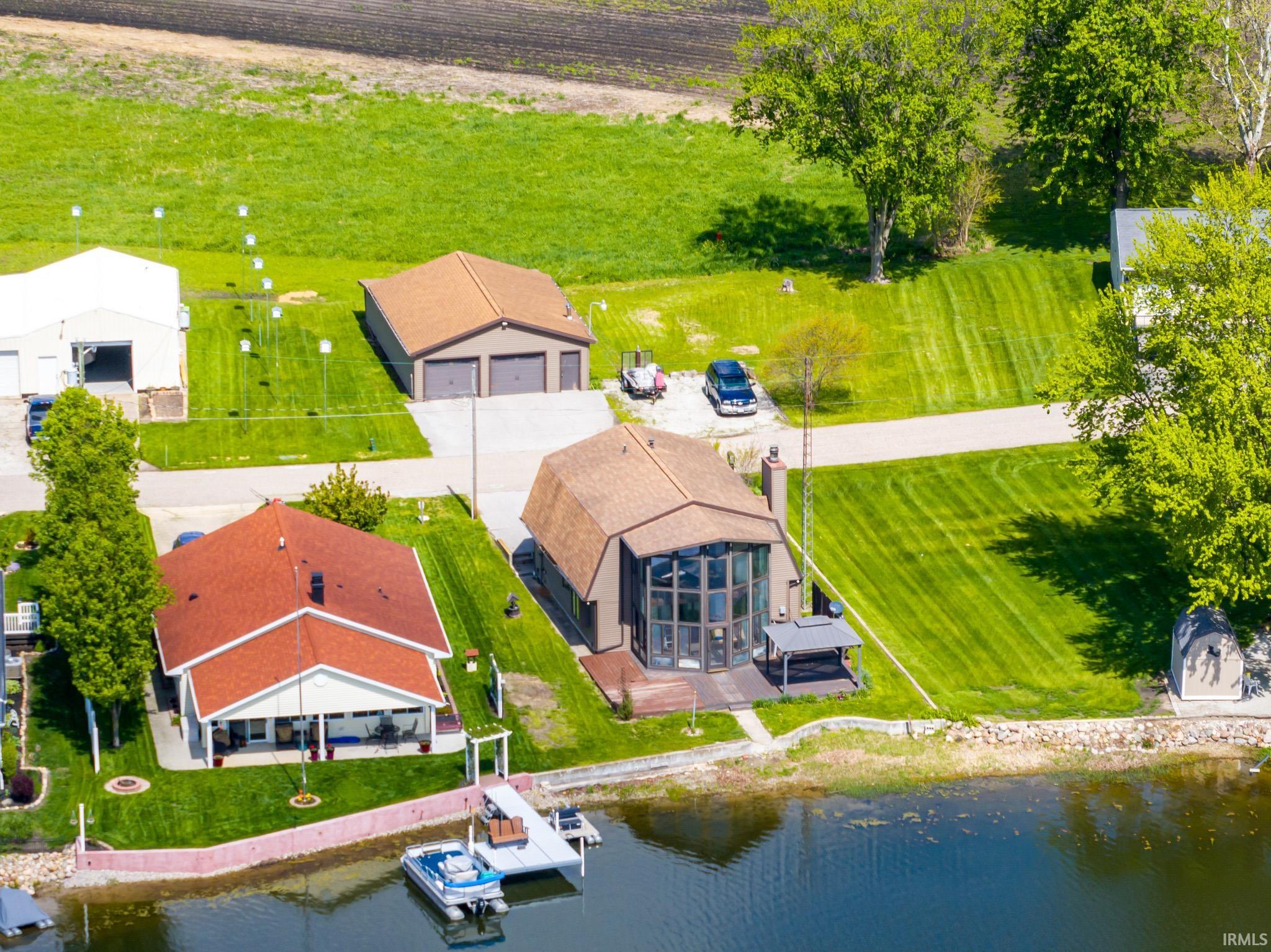 Waterfront property featuring a private dock, expansive green space, and a red-shingled roofline