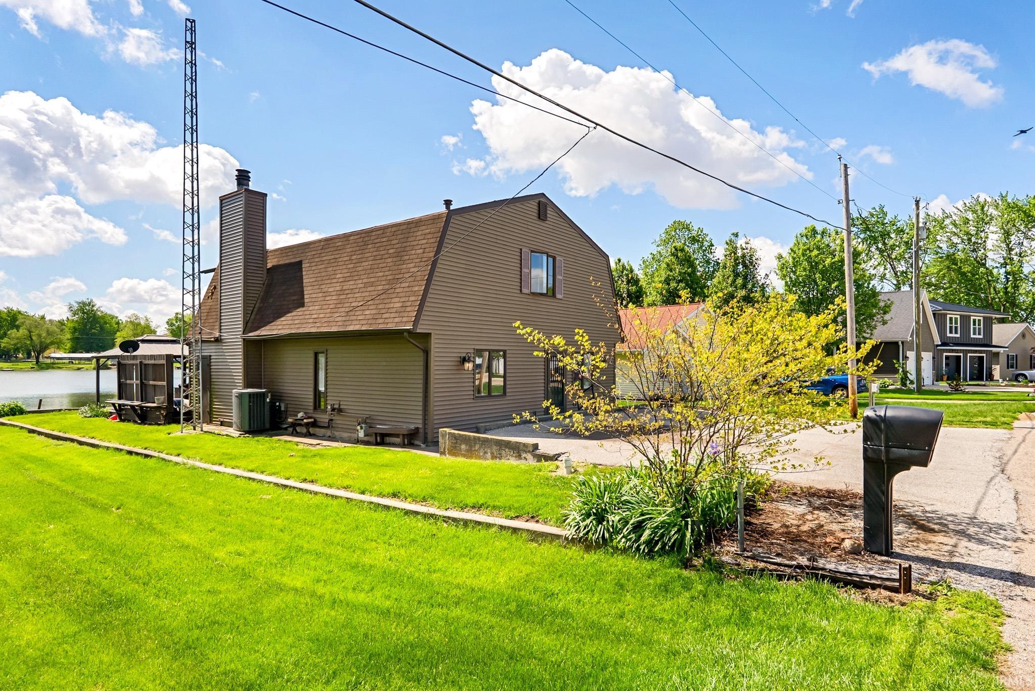 Exterior siding residence featuring a gambrel roofline, prominent chimney, and multiple windows