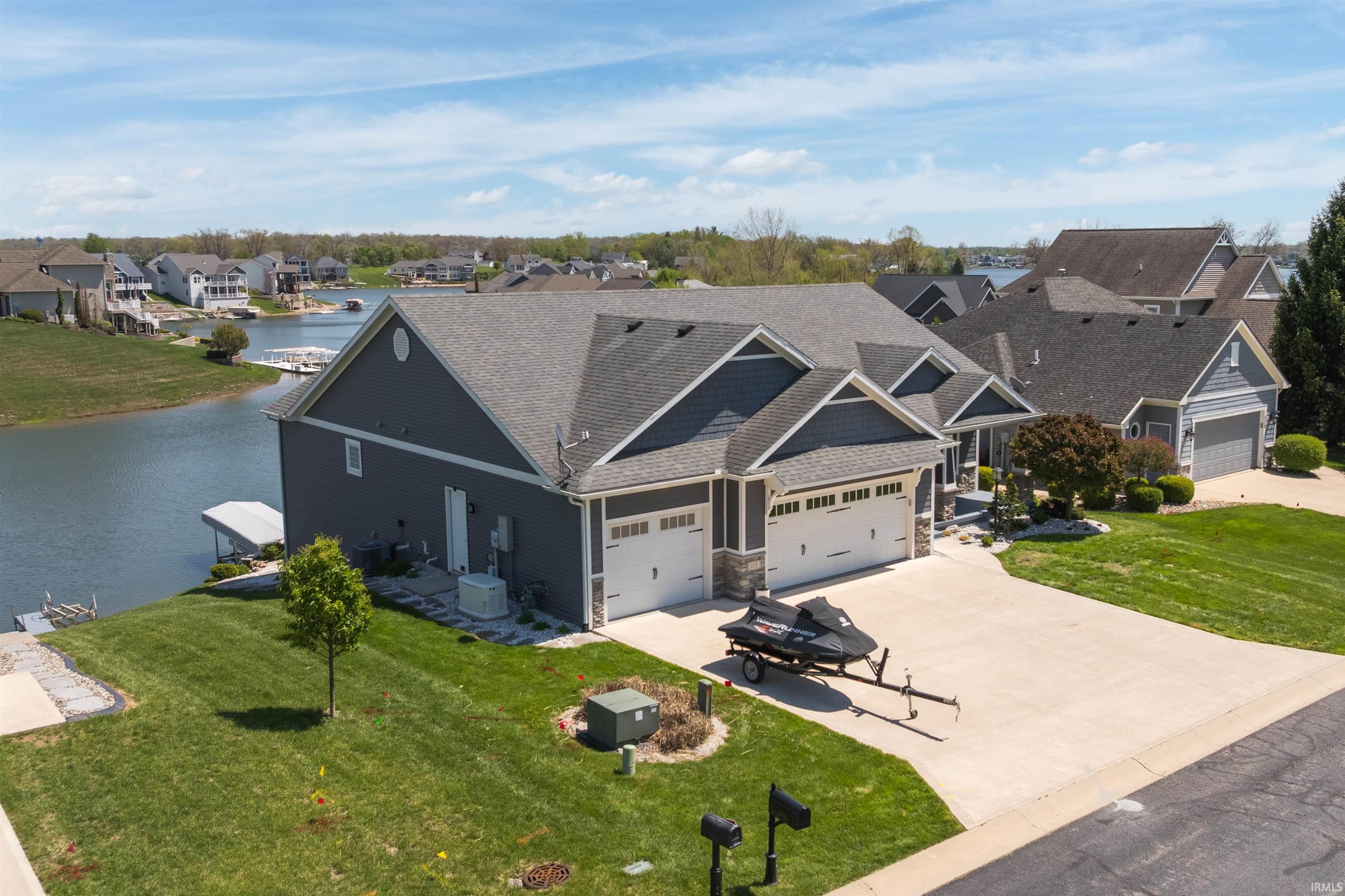 Waterfront residence featuring a multi-car garage, gray siding with white trim, and a concrete driveway