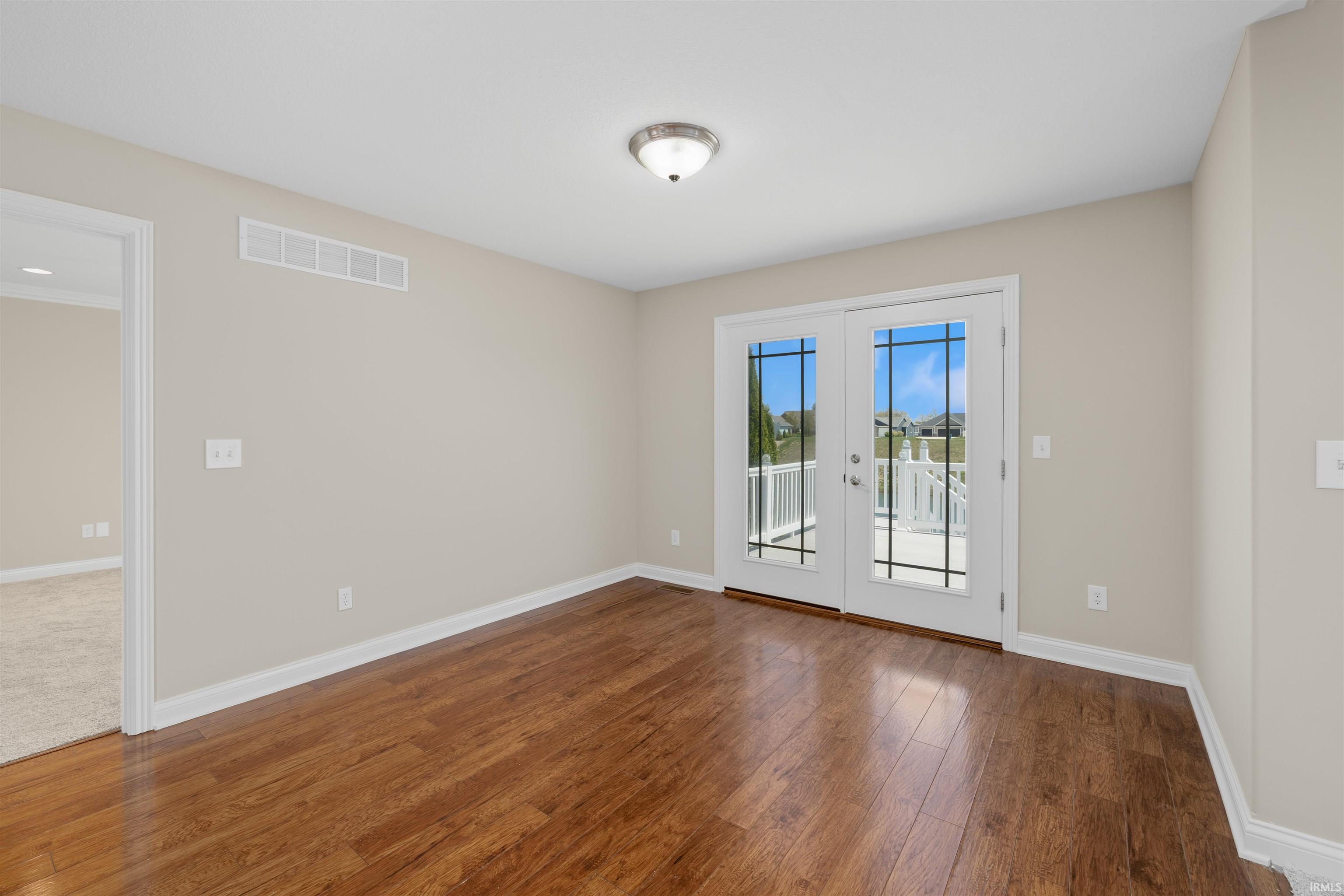 Room featuring wood-finish flooring, light-toned walls, and white trim