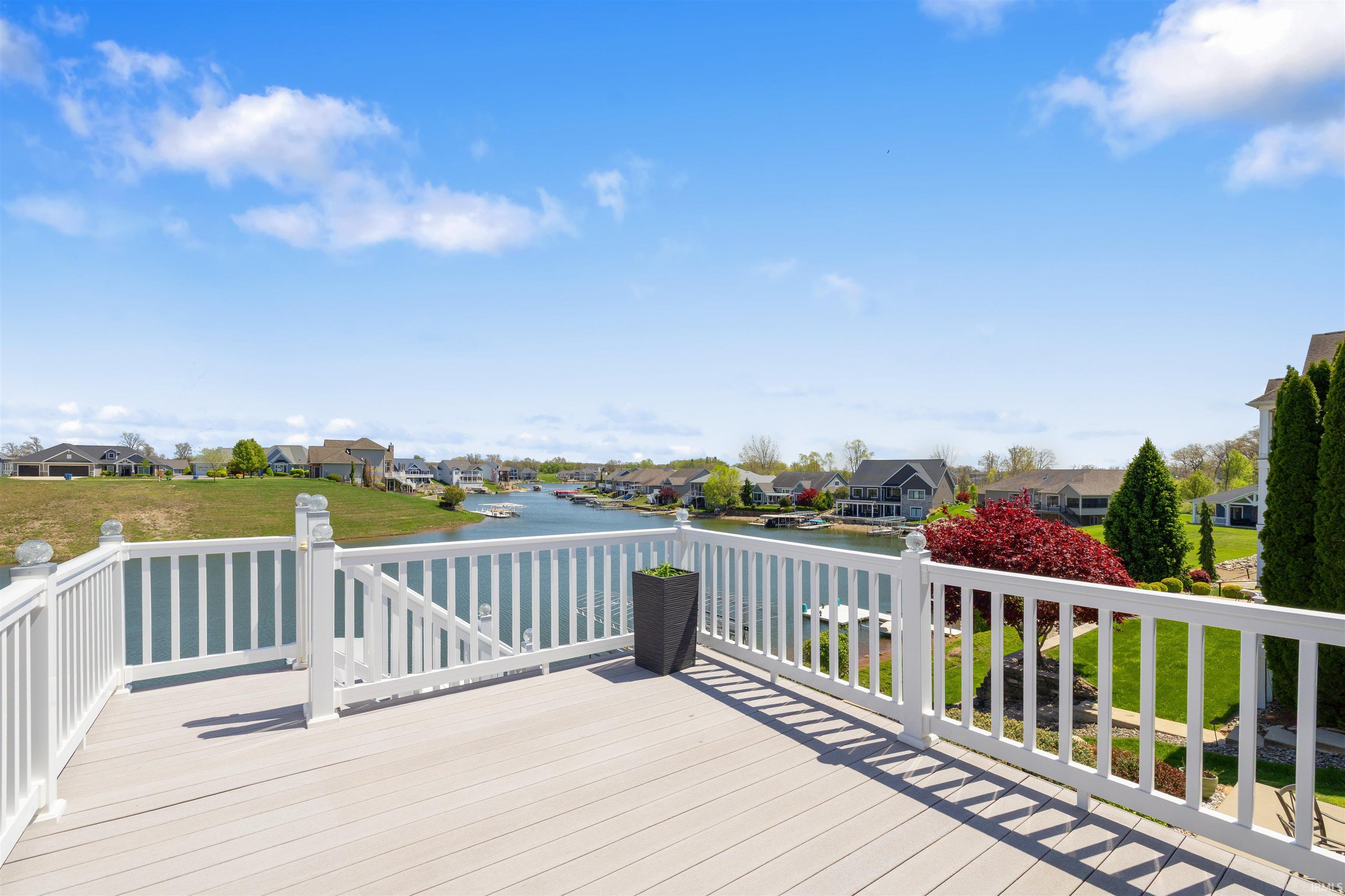 Expansive elevated deck with composite decking and white railing, overlooking a waterfront landscape
