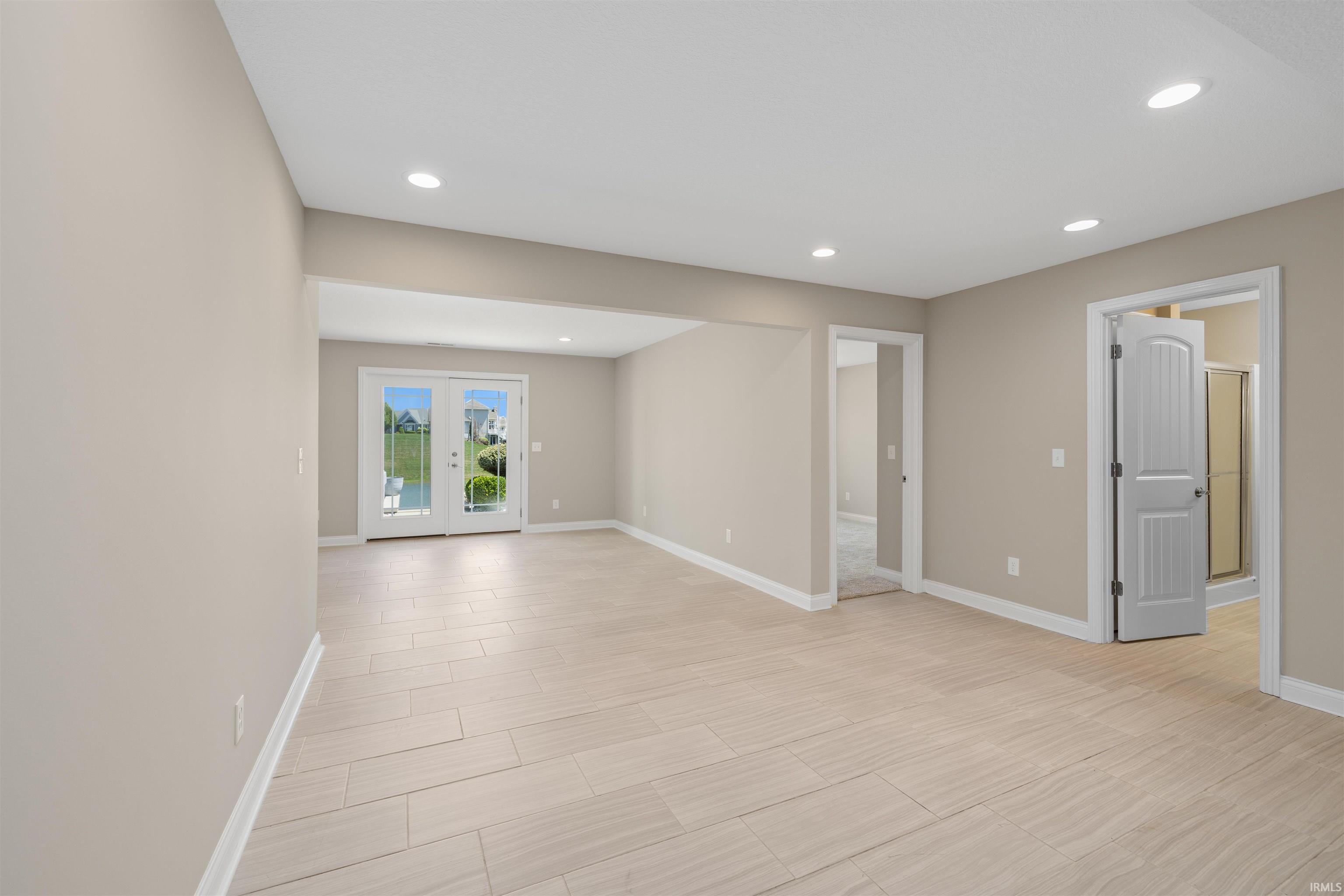 Spacious room featuring light-toned wood-finish flooring, recessed lighting, and neutral wall tones