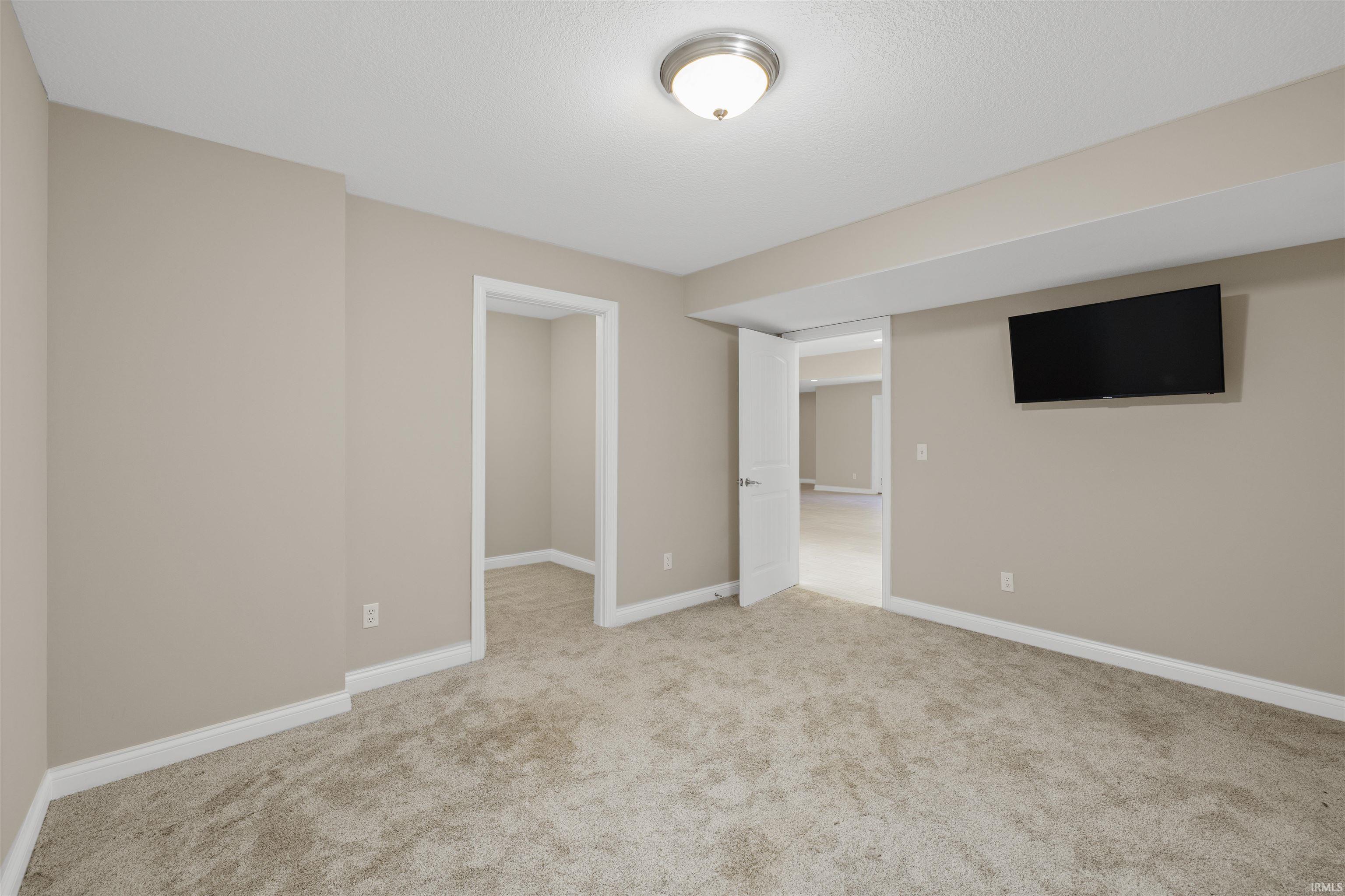 Neutral-toned room with plush carpeting, white baseboards, and a semi-flush ceiling light fixture
