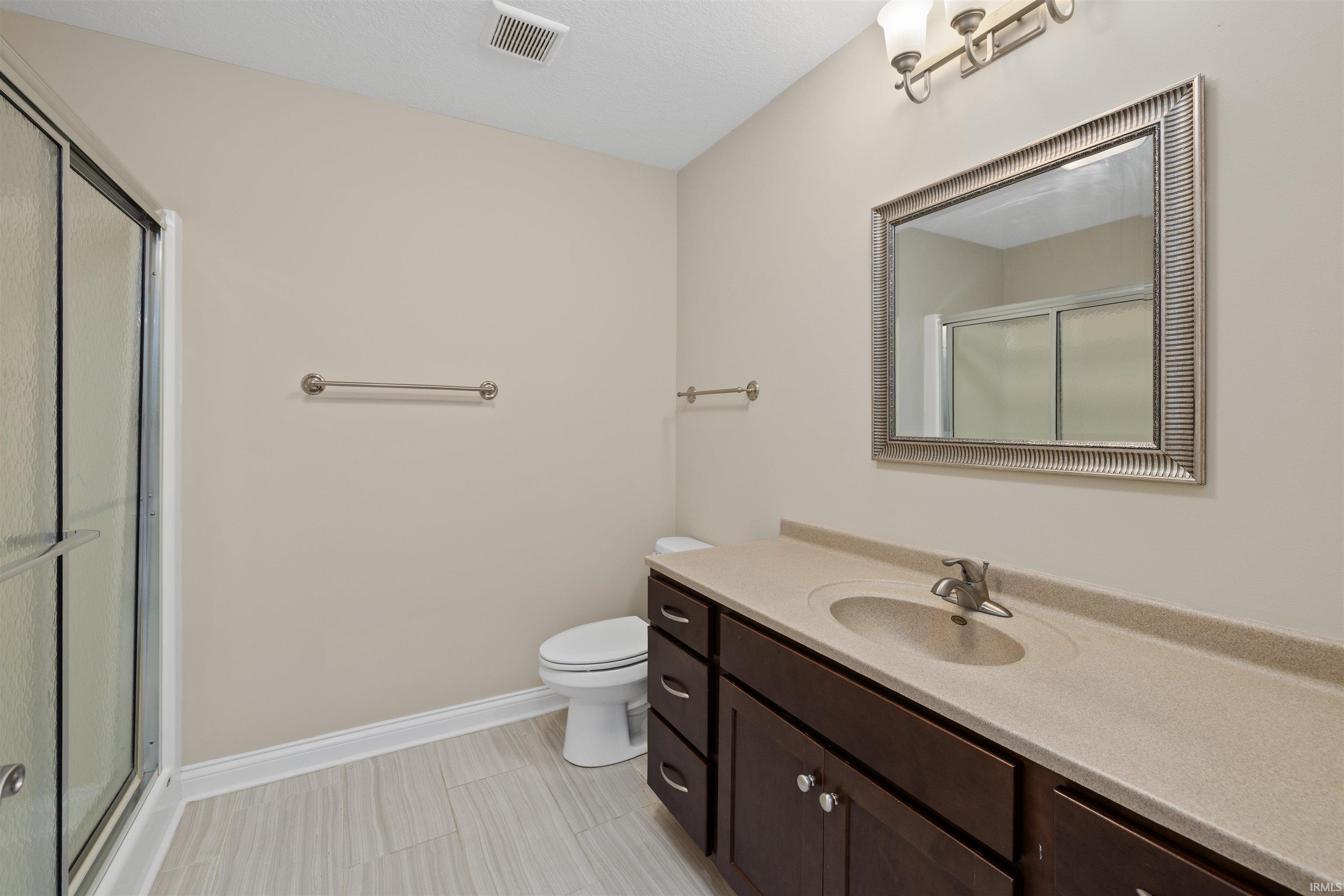 Bathroom featuring a single vanity with built-in sink, framed mirror, and a shower with glass enclosure