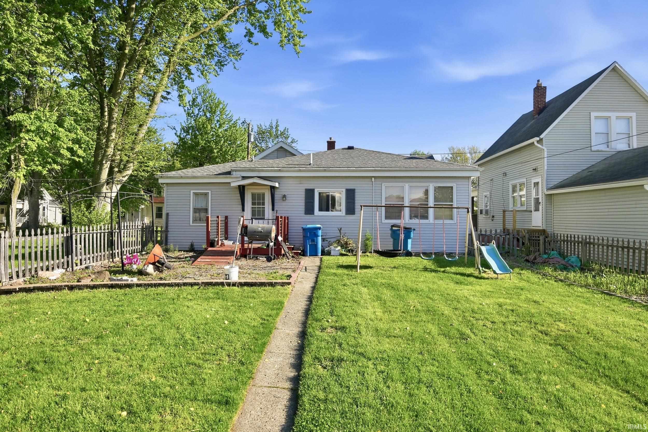 Expansive backyard with a concrete pathway leading to the home's rear entrance
