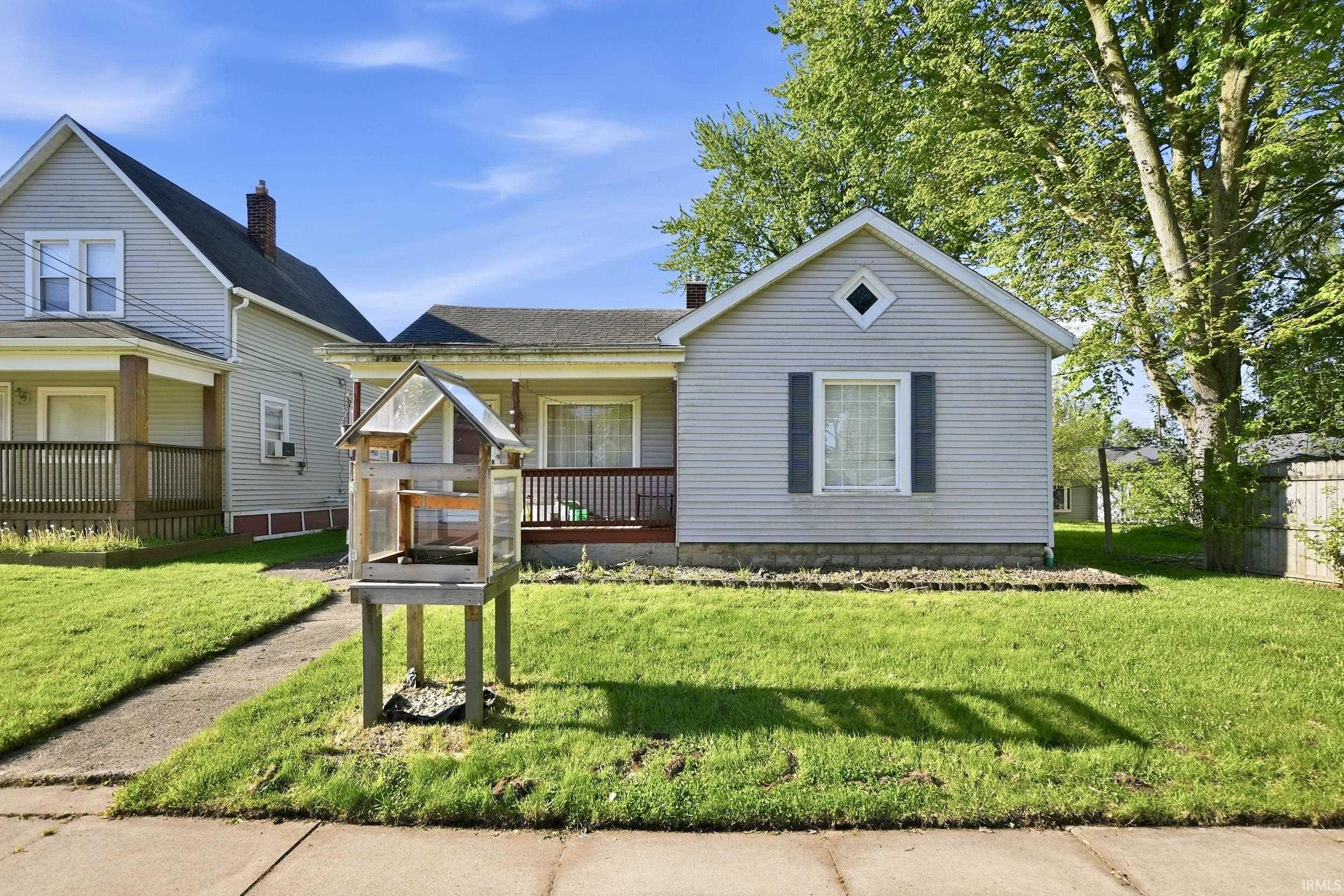 Single-story residence featuring light gray siding, a covered front porch, and a dormer window