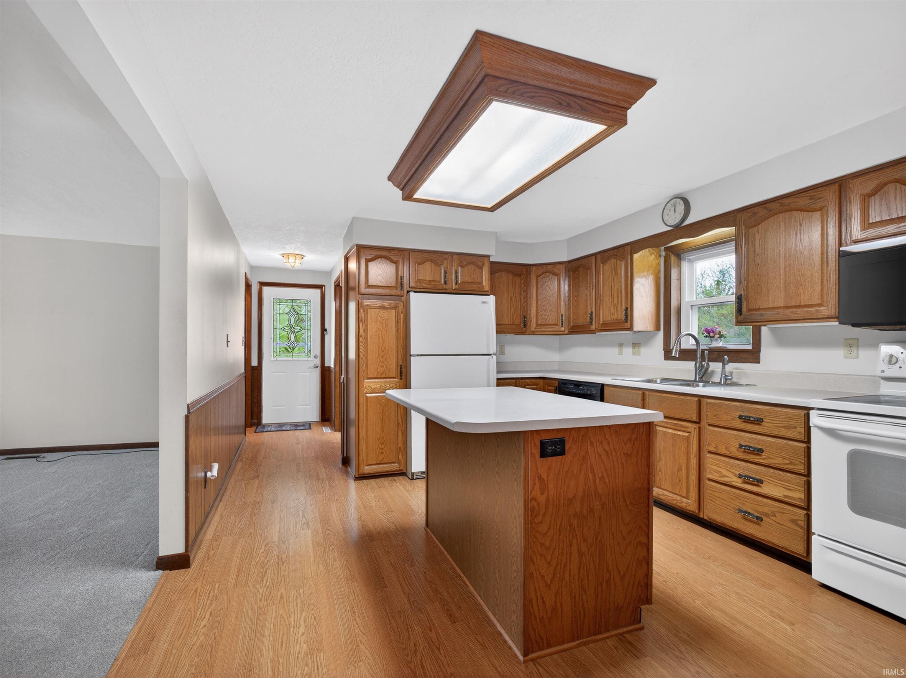 Kitchen featuring wood-finish flooring, a central island with countertop, extensive wood cabinetry, and white countertops