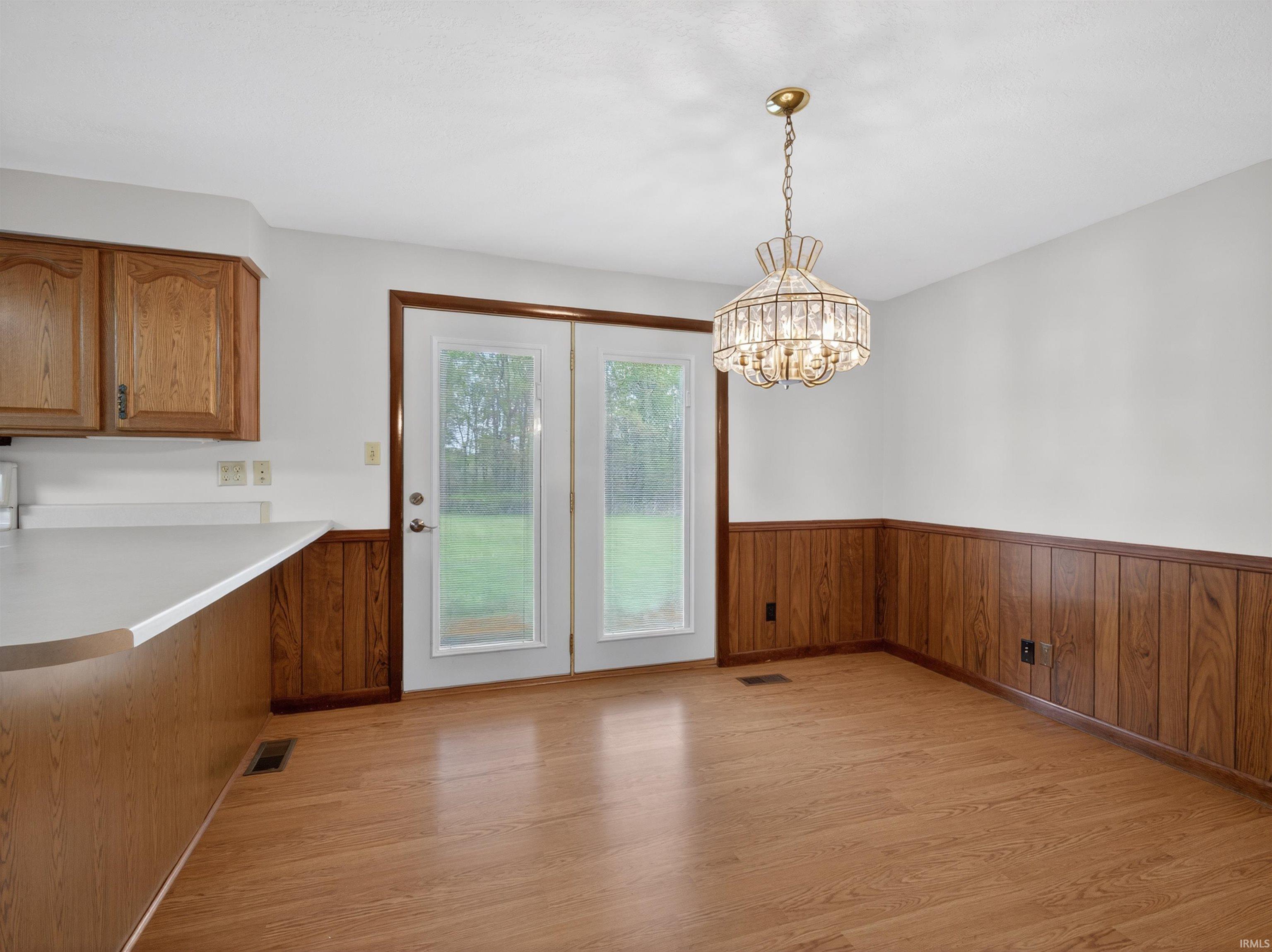 Dining area featuring a crystal chandelier, wood-finish flooring, and wood paneling