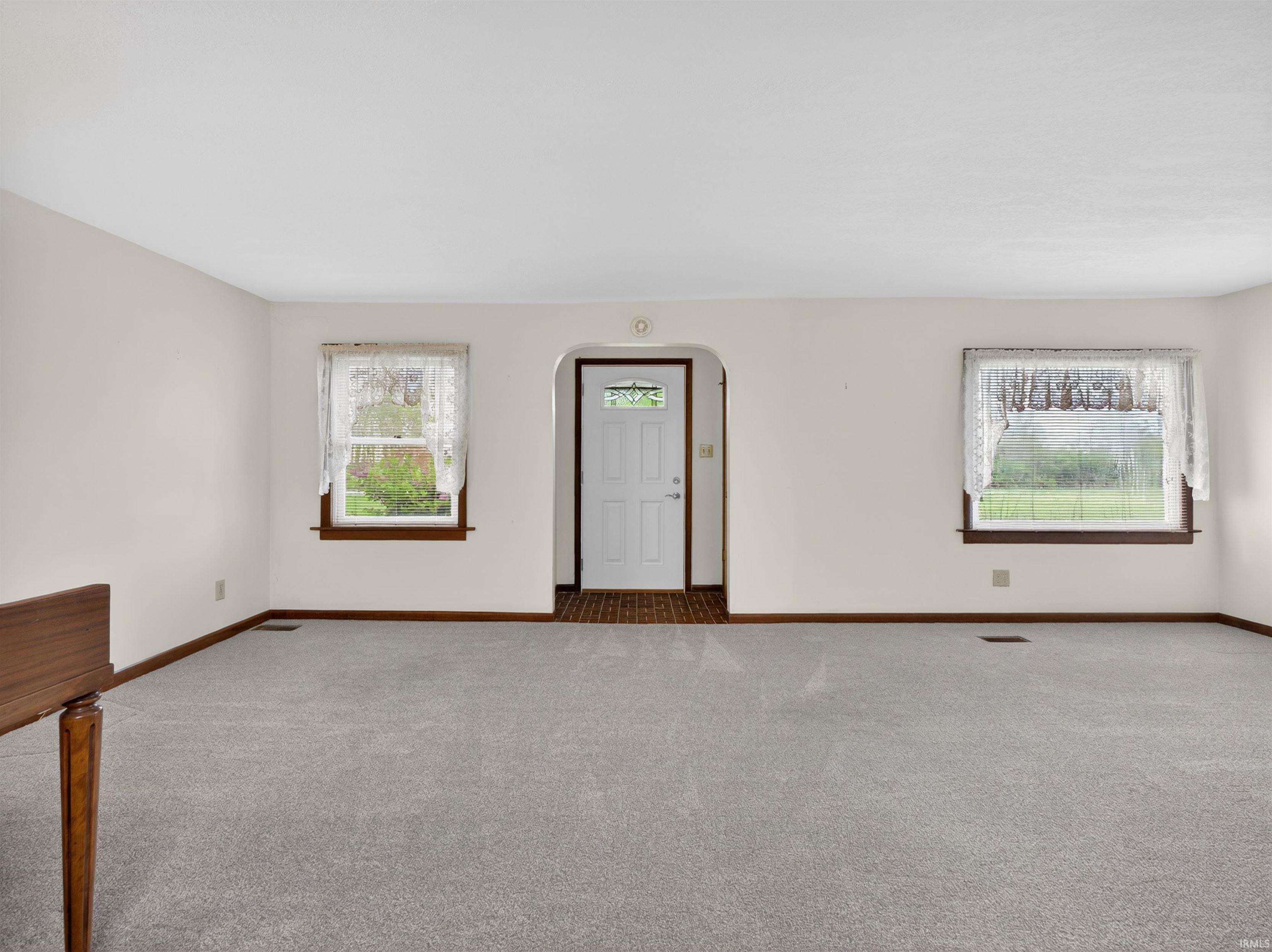 Entryway featuring a white paneled door with decorative glass, flanked by two windows with wood-trim sills